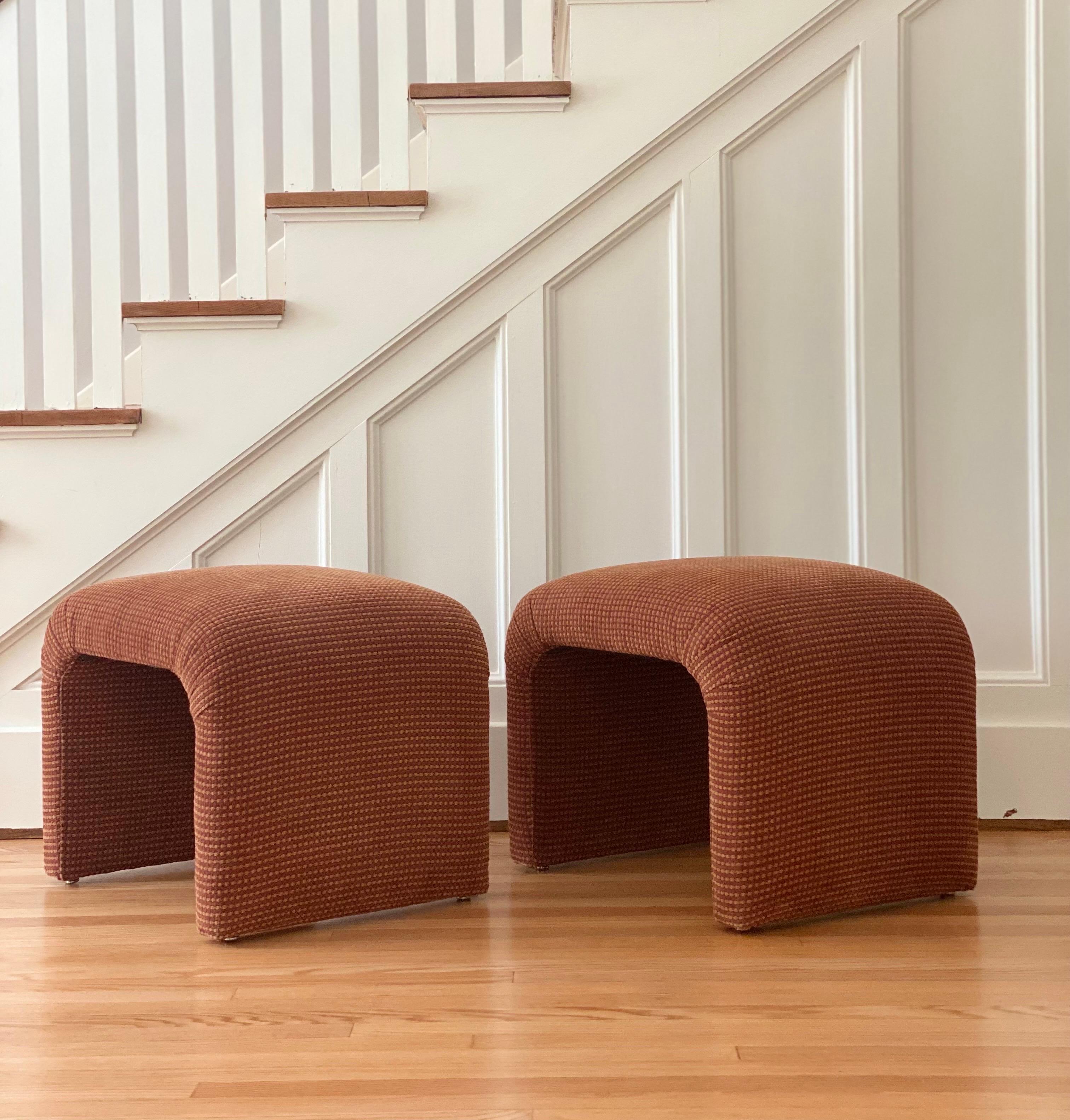 We are very pleased to offer a chic, vintage pair of Karl Springer style ottomans, circa the 1980s. Spotting a boldly curved silhouette, each piece is wrapped in its original shepherd’s check pattern upholstery. Fabric is soft to the touch and in
