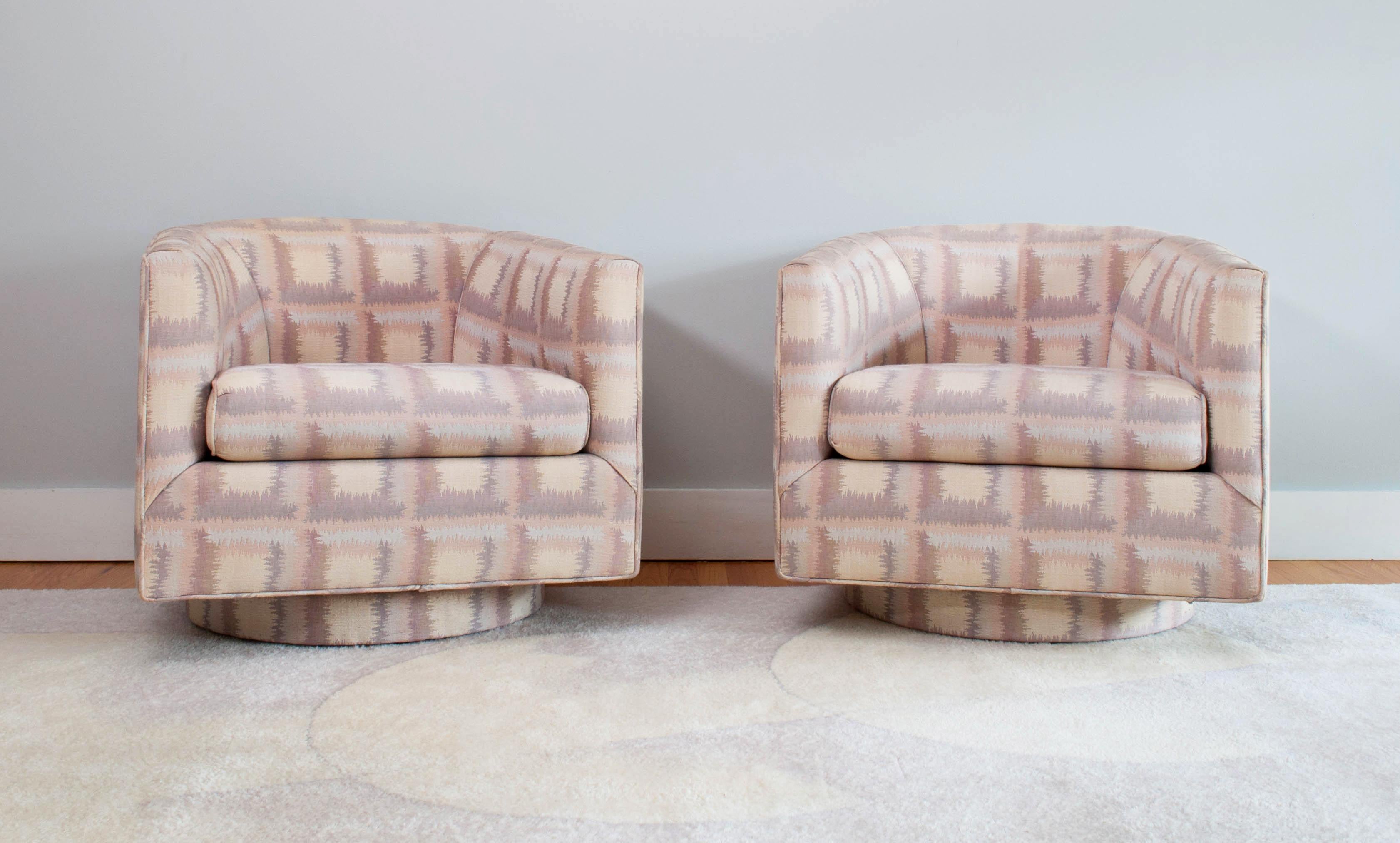 Stylish pair of 1986 vintage swivel barrel back club chairs by Kessler Industries with an upholstered platform base and eye-catching graphic pink and purple pastel fabric. The comfort and proportion of the chairs speaks to their exceptional