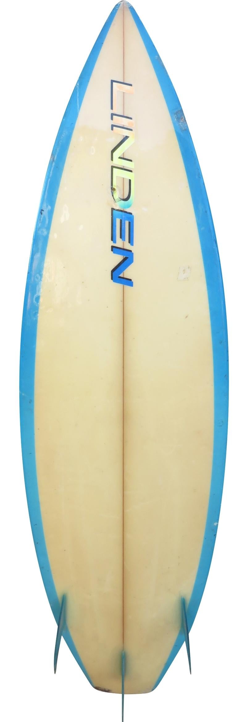 1980s vintage linden surfboards thruster (tri-fin) shortboard. Features a multi-ray design on deck with channel bottom and blue airbrushed rails. A great example of a 1980s surfboard.