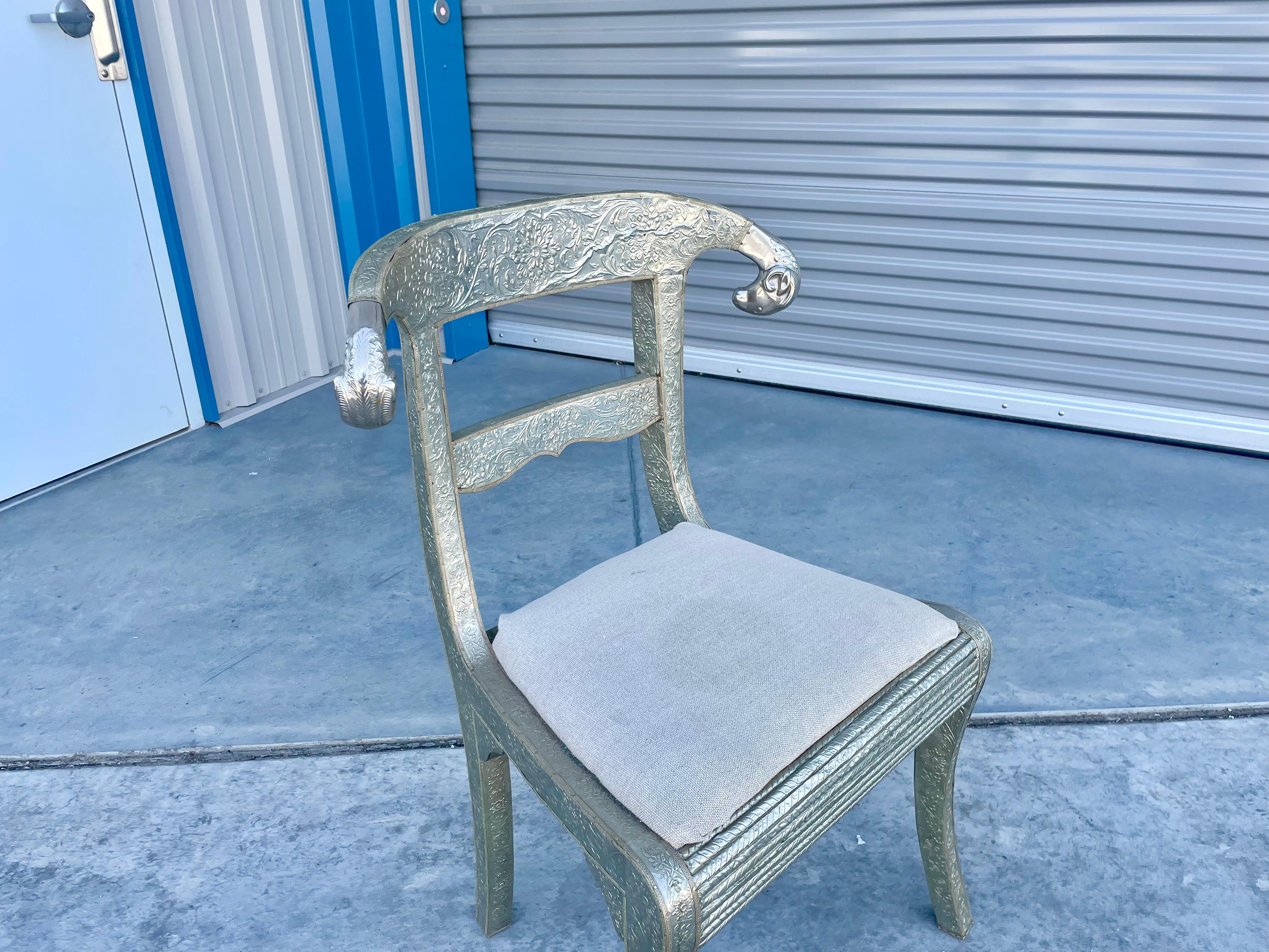 Vintage metal-wrapped ram chair designed and manufactured in India circa 1980s. This beautiful chair is also called a wedding chair. It features a wooden frame wrapped in silver metal and polished ram heads on the sides, giving it a great