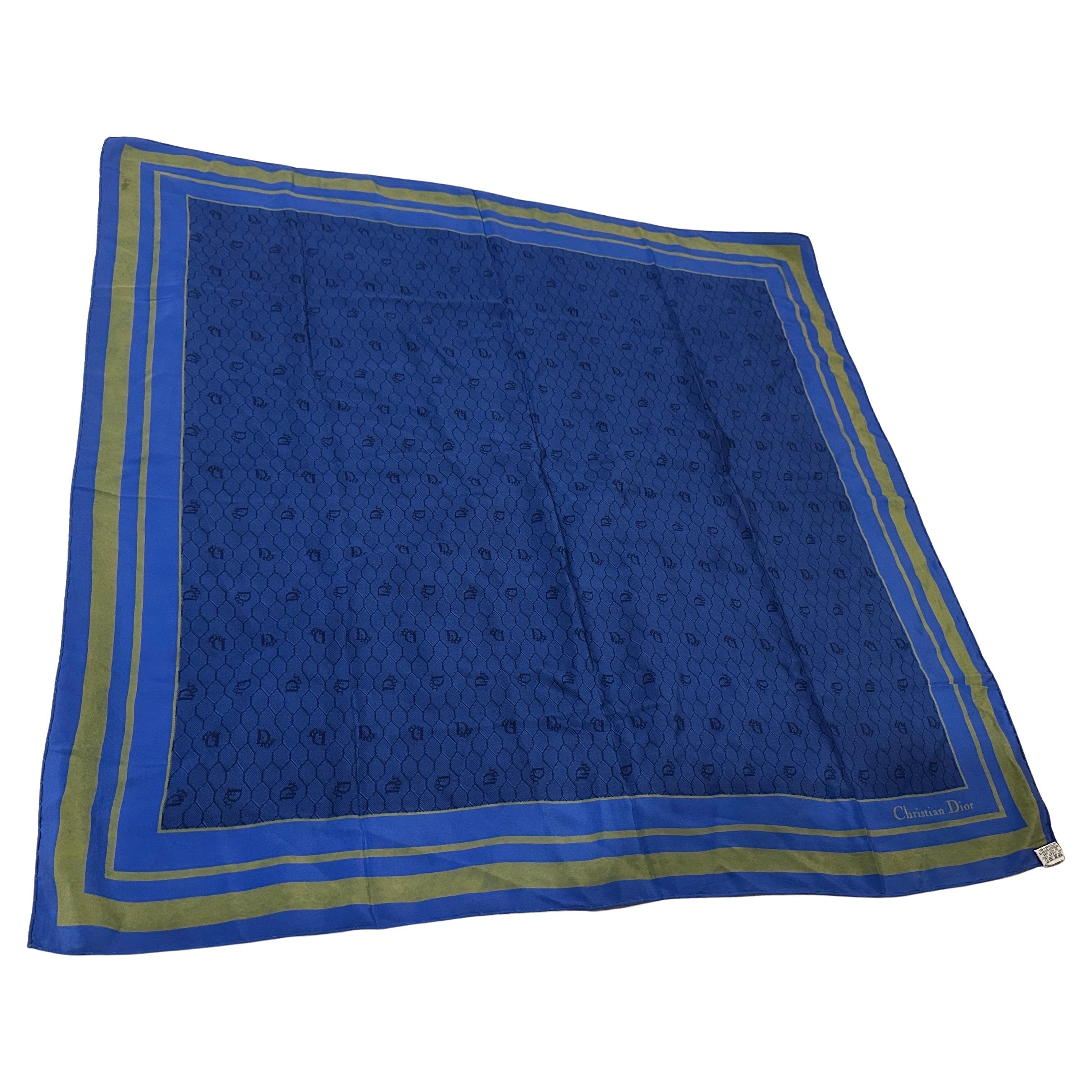 Cette écharpe en soie vintage des années 1980 de Christian Dior est d'un bleu royal saisissant et présente un motif géométrique raffiné subtilement tissé dans le tissu. La bordure est composée de rayures superposées dans des tons complémentaires de