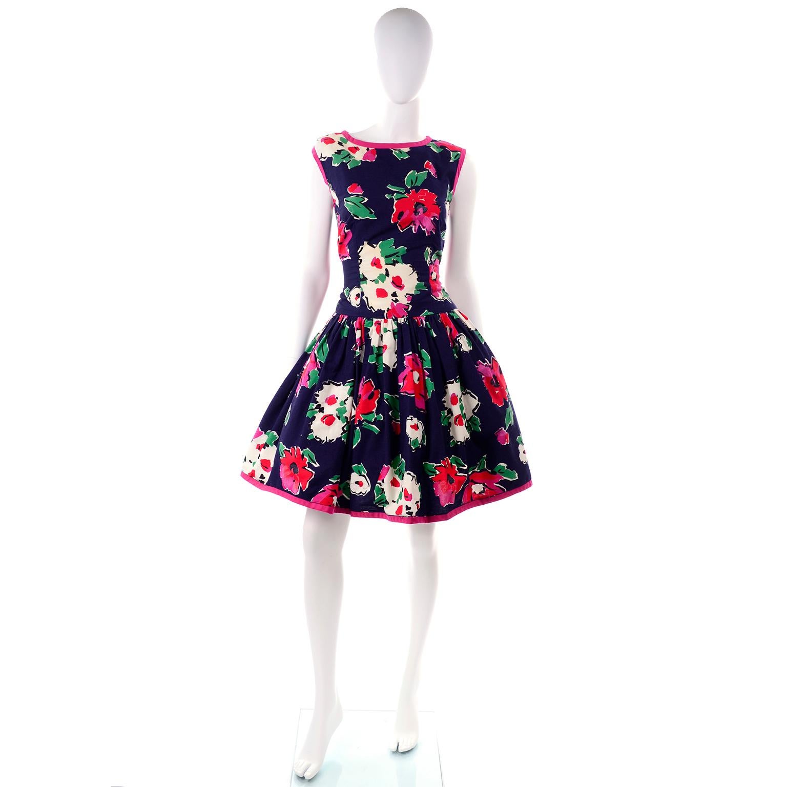 This is a fun 1980s Victor Costa vintage floral dress with bright pink trim in a navy blue cotton with red, white, cream and pink flowers.  The dress has a great open back with a pretty bow at the waist and it closes with a back zipper.  There is a