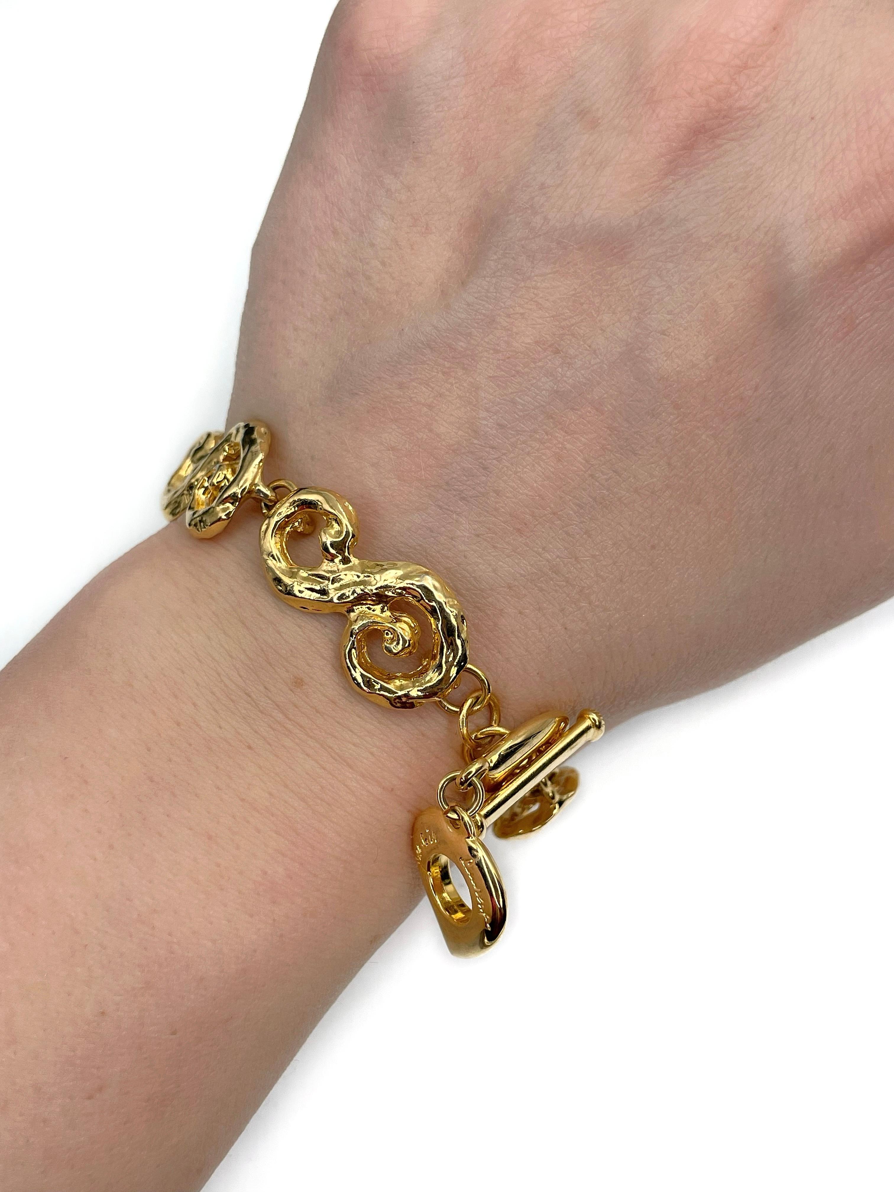 This is a gold tone arabesque pattern bracelet designed by YSL in 1980’s. The piece is gold plated. 

Signed: “Yves Saint Laurent” (shown in photos).

Adjustable toggle and loop closure.

Adjusts to 17cm and 19.5cm wrists
Whole bracelet length: