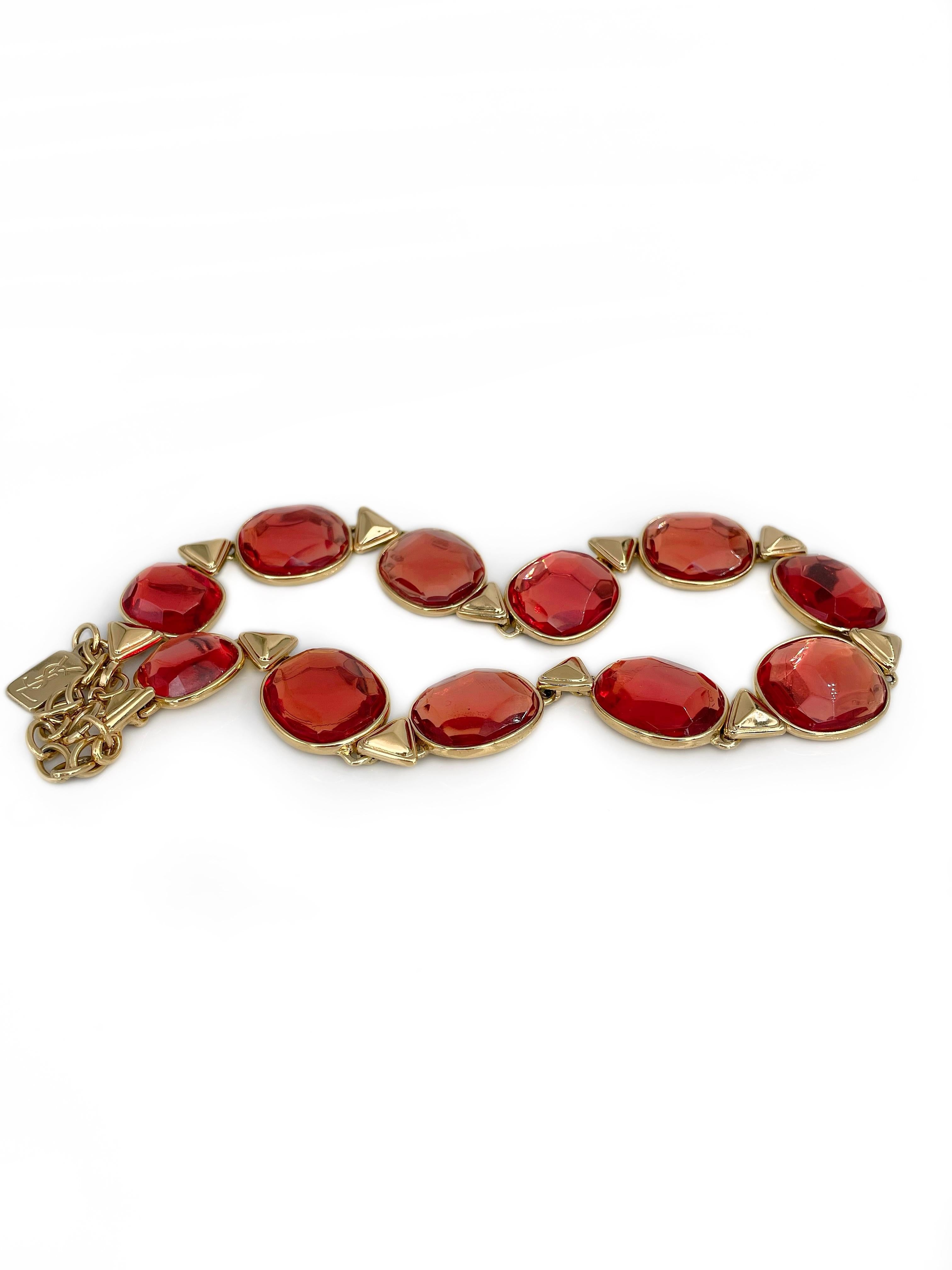 Si tratta di una collana a maglie dorate disegnata da YSL nel 1980. Il pezzo è placcato in oro e presenta una resina sfaccettata rosso-arancio. 

Nella nostra inserzione c'è un braccialetto adatto della stessa collezione. 

Firmato: