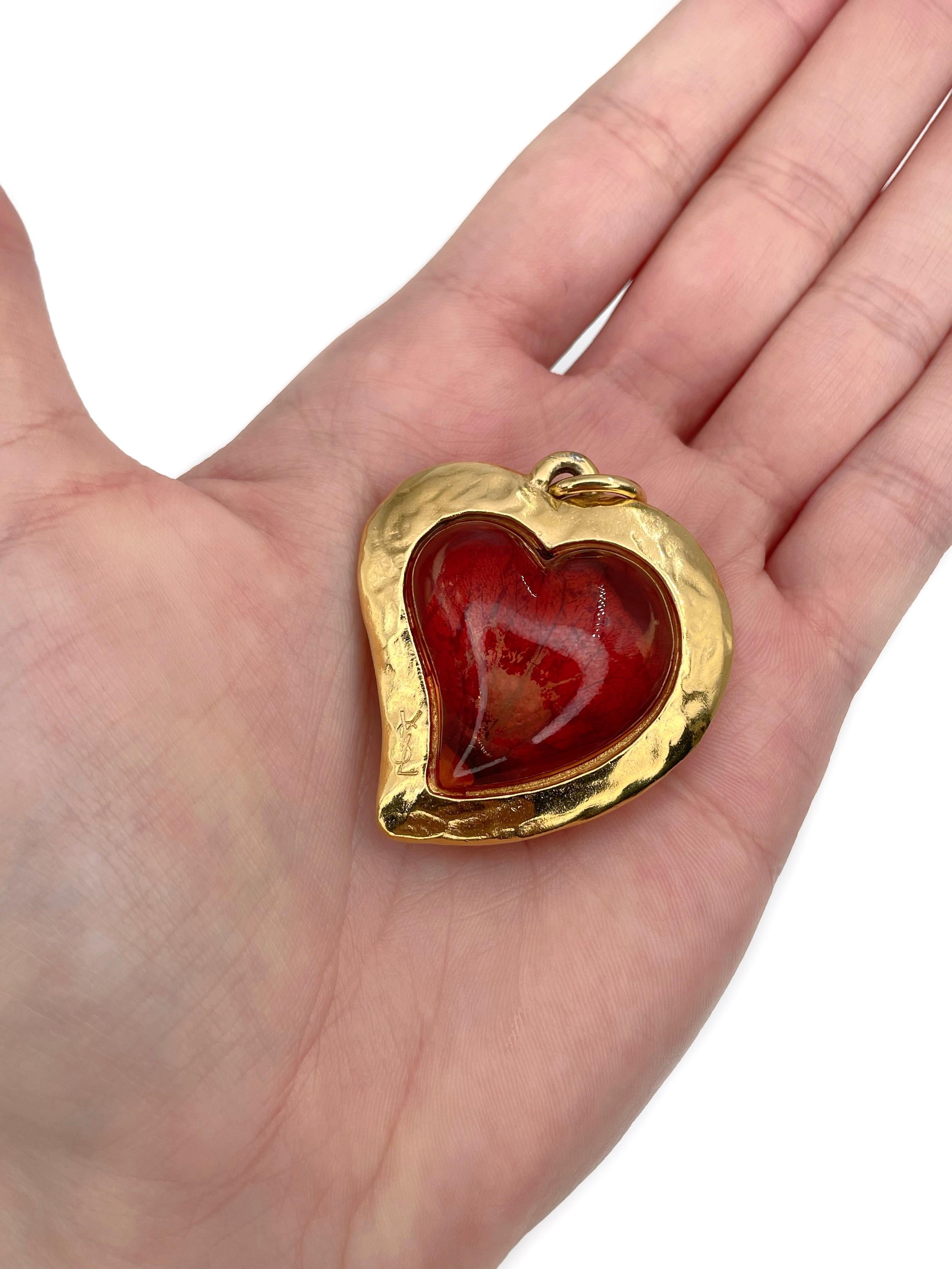 Il s'agit d'un pendentif vintage en forme de cœur conçu par YSL dans les années 1980. La pièce est plaquée or. Il est composé de résine orange rougeâtre et de pétales de rose. 

Signé : 