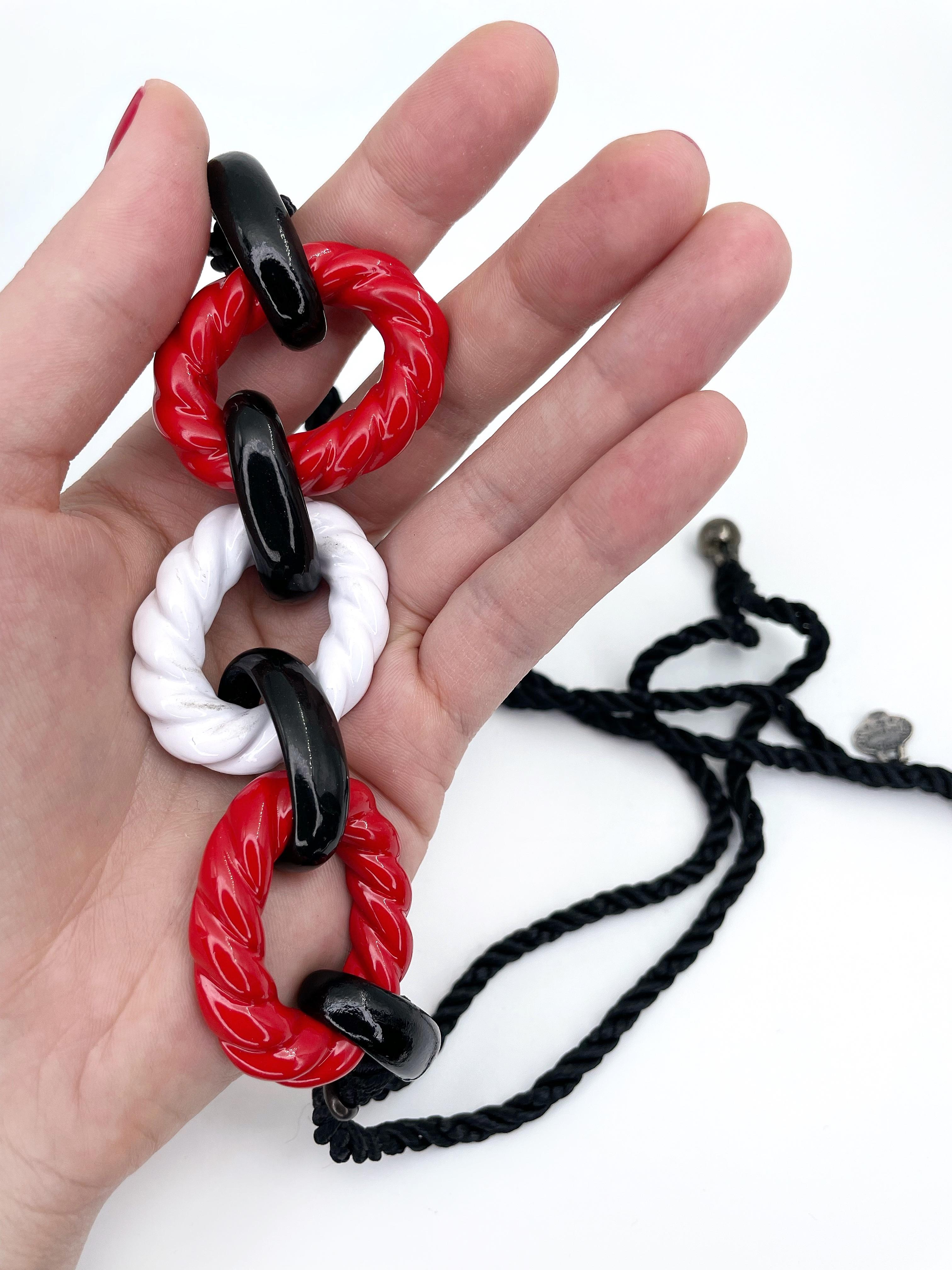 This is a colourful nautical design rope necklace created by YSL in 1980’s. The piece features red, white and black enamelled metal link details in the centre. The black twisted silk cord is finished with beads. 

Signed: “Yves Saint Laurent - Rive