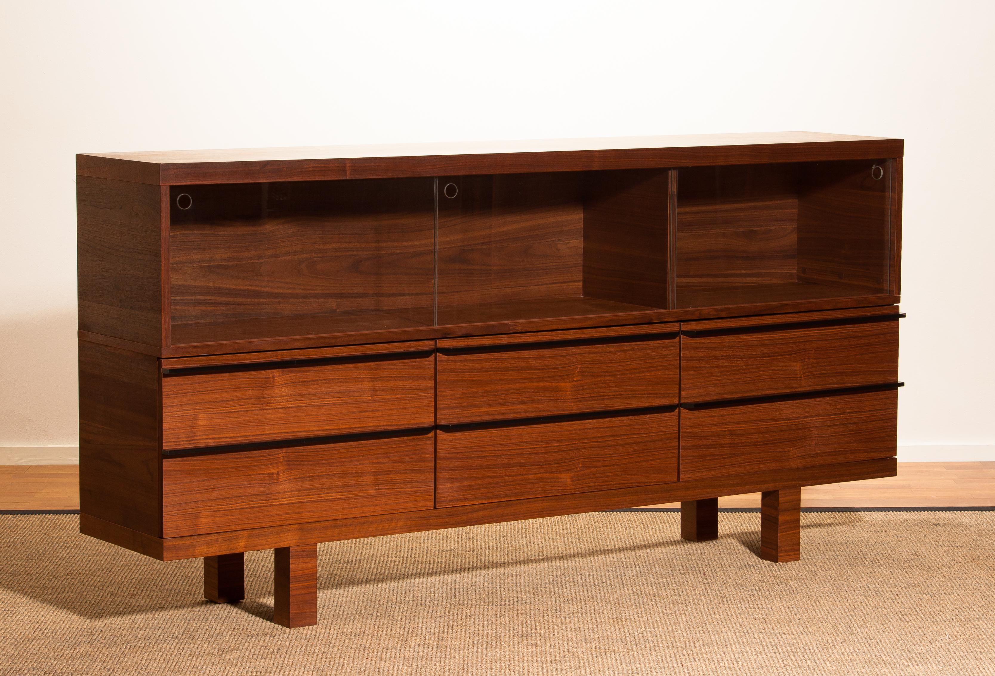 Beautiful sideboard made of walnut veneer.
Three glass sliding doors (vitrine top) and three doors with a six drawers optic.
Period 1980s.
The dimensions are W 180, H 90, D 35.
The height of the glass vitrine is 30 cm.