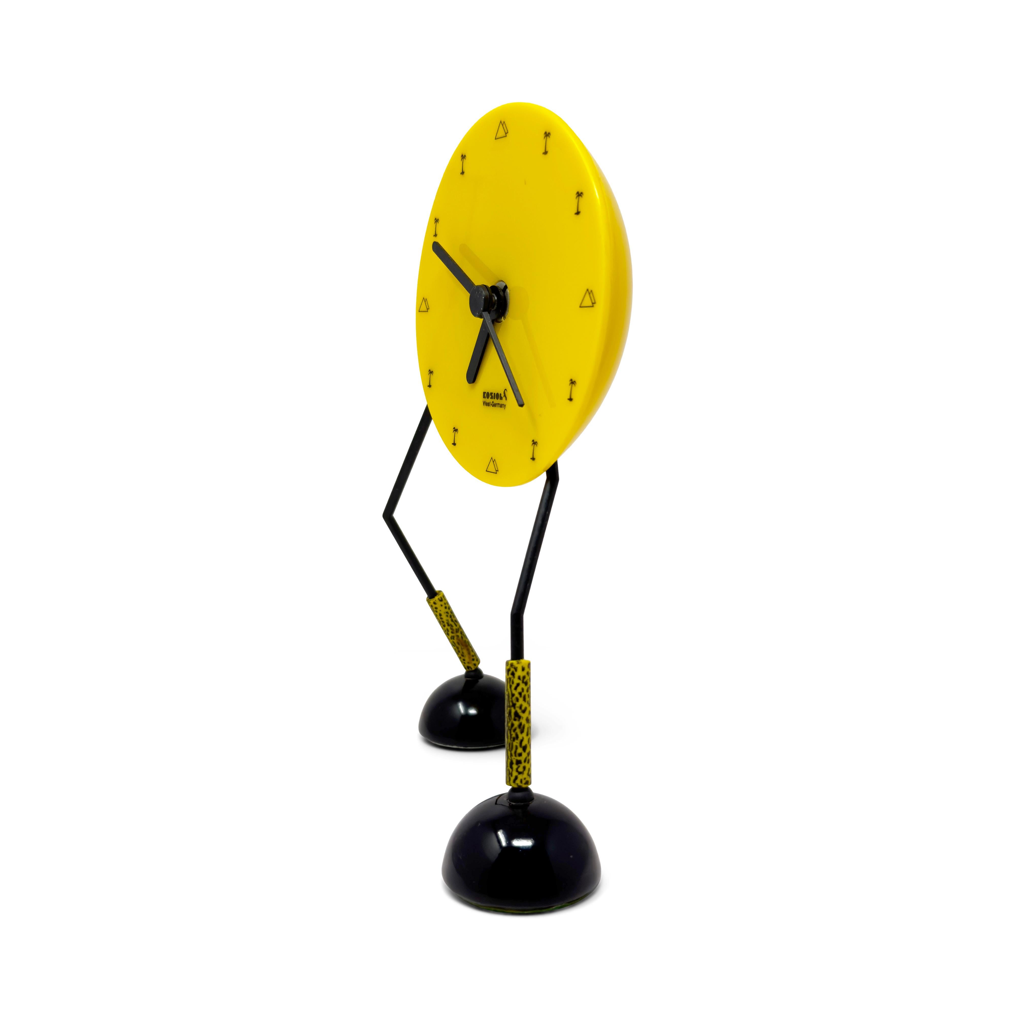 An incredibly charming West German postmodern vintage desk, mantel, or shelf clock with so much personality!  The clock has a yellow plastic case with black numbers and hands, but it stands on a pair of legs that make it look like the clock is going