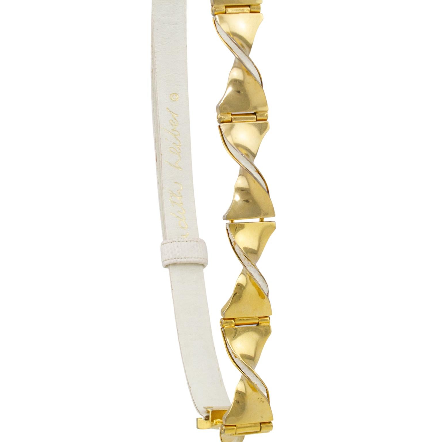 1980's Judith Leiber belt. White patterned leather with gold tone twisted details across the front. Adjustable to be worn at waist or at hips. Gold Judith Leiber logo stamped on interior white leather lining. Excellent vintage condition. Fits from a