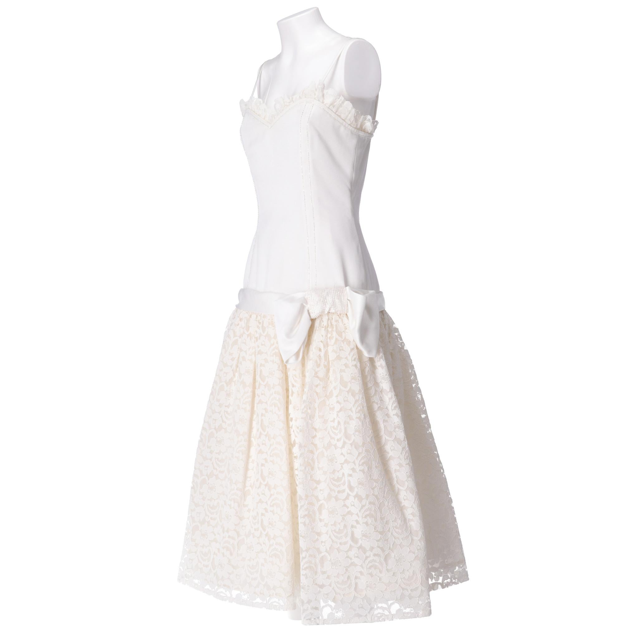 White tailored wedding dress, with layered bell-shaped skirt in lace and tulle long up to the ankles, sweetheart neckline with shoulder straps, large bow on the side with decorative beads.

Years: 1980s

Made in Italy 

Size: 42 IT

Linear