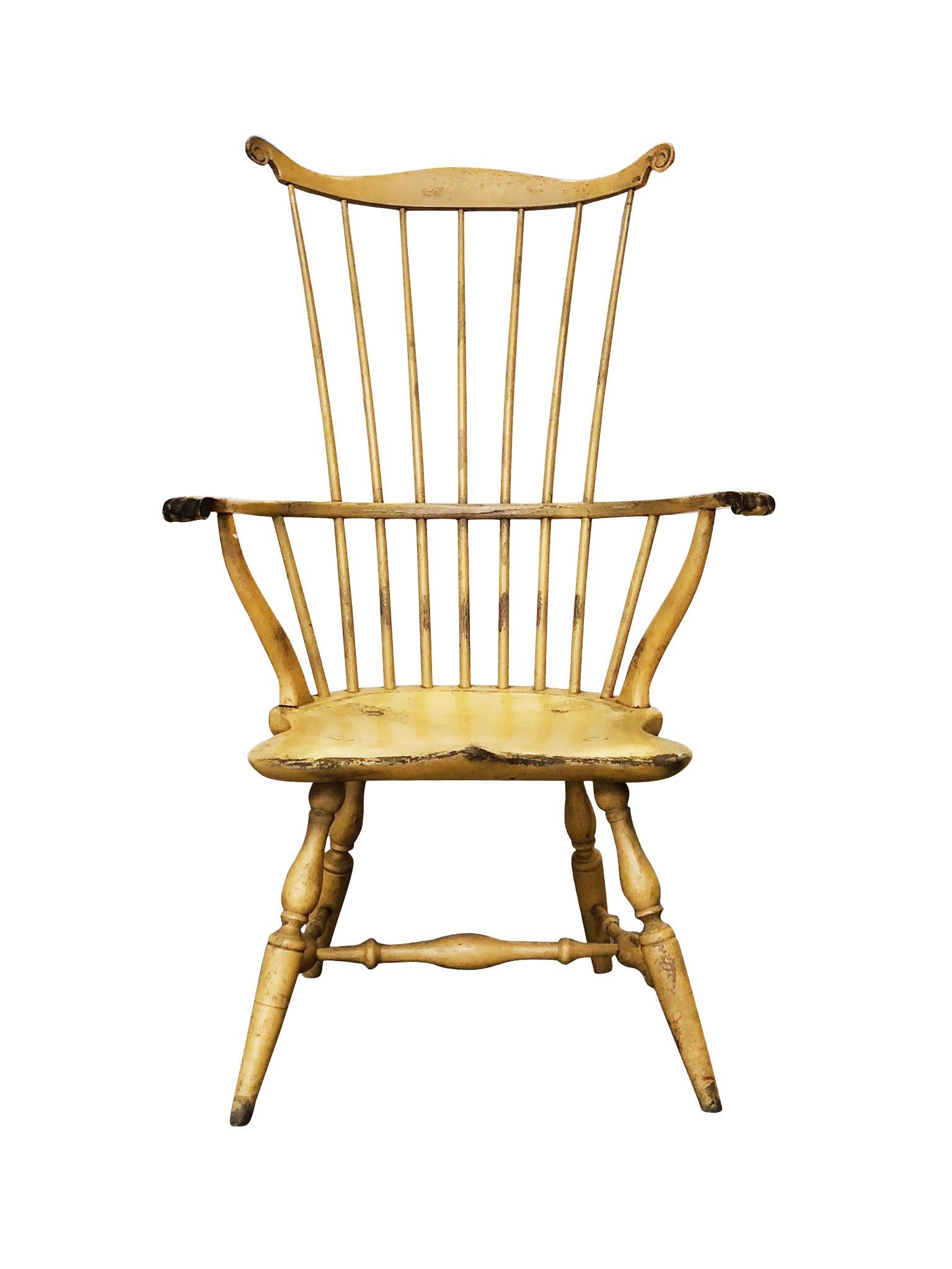 A Windsor-style chair handcrafted by Bill Wallick. Made from poplar wood and hand painted in a yellow coat that has been enriched with texture and wear over the years. The chair is faithful to a Classic Windsor design: a spindle back, a wing-tipped