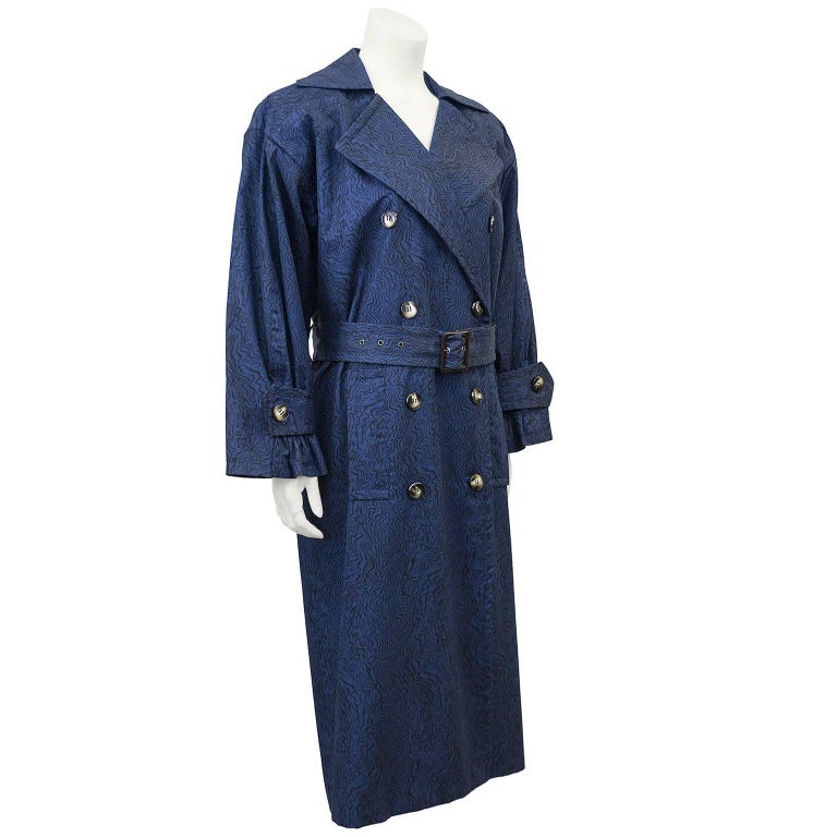 YSL classic styled trench coat from the 1980’s. Strong emphasis on the shoulder reflects the focus of YSL design in that decade. Double breasted and belted in the classic silhouette of a trench, there is an added twist in the subtle wave pattern in
