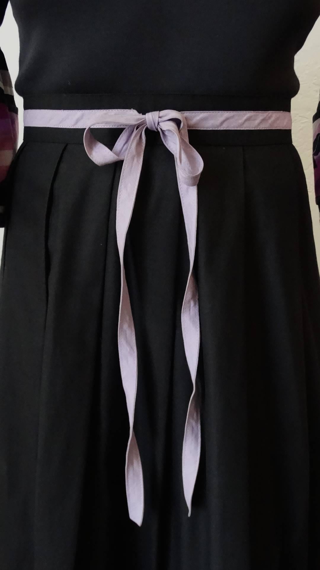 Incredible late 1970s-1980s Yves Saint Laurent Rive Gauche maxi dress! Solid black fabric contrasted with lavender and purple striped details along the hem and sleeves. Adorable bell sleeves that flare out at the cuffs. Lavender bow around the