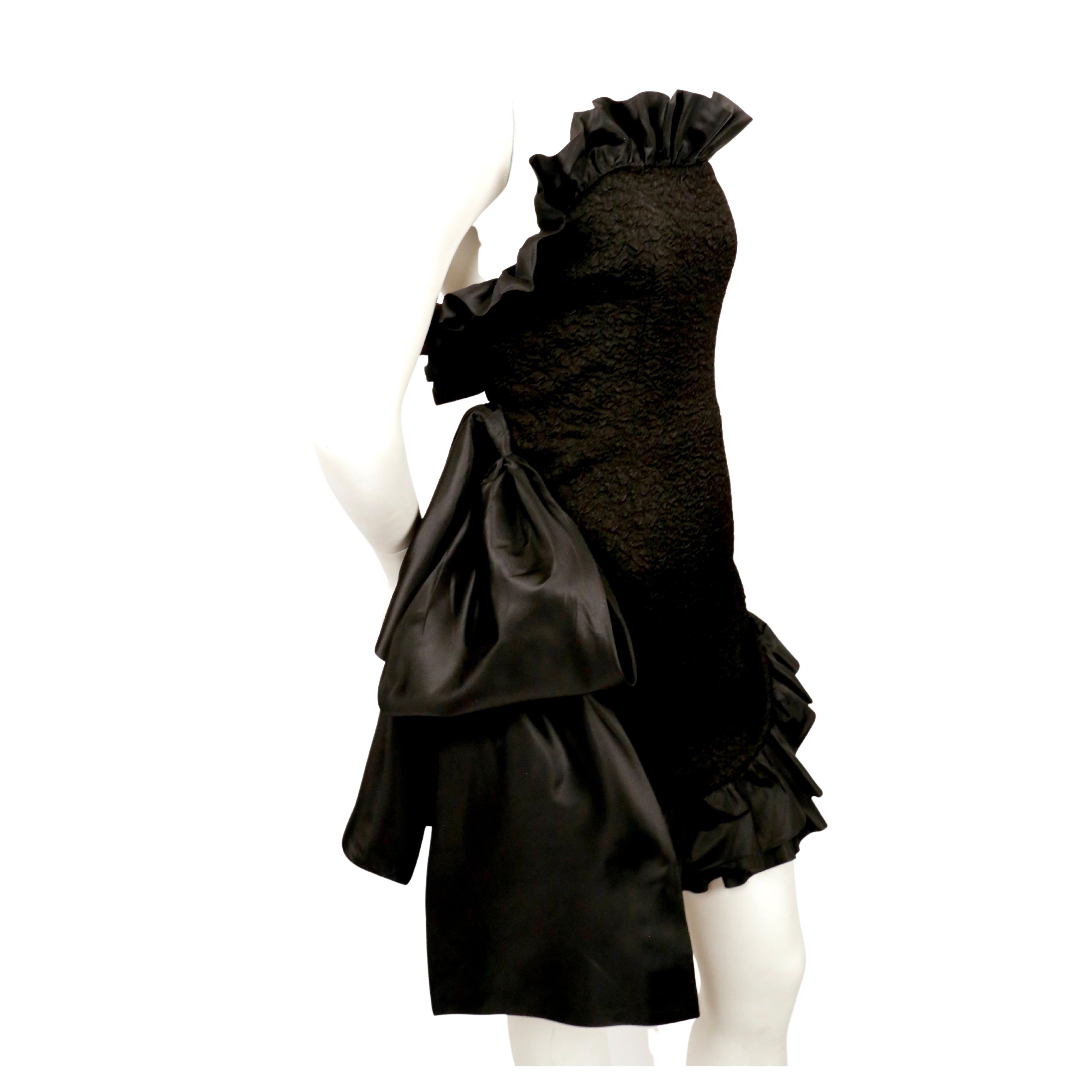 Dramatic, jet-black textured dress with satin ruffled trim and large bow designed by Yves Saint Laurent dating to the 1980's. Fully internal corset with boning at bodice. Labeled a French size 38. Approximate measurements: bust 32