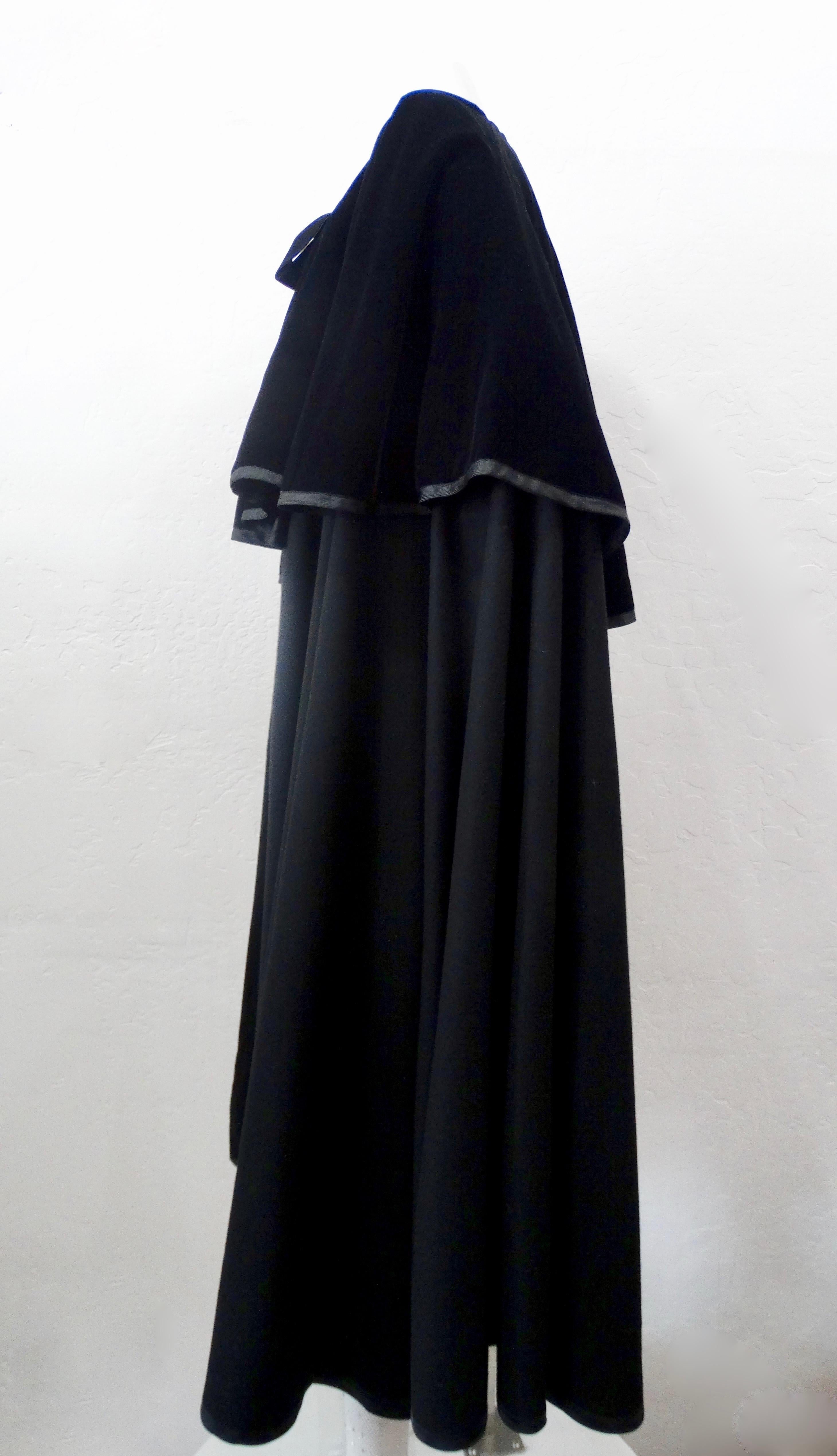 Elevate your wardrobe with this amazing YSL cape! Circa 1980s, this cape is made of black wool and features a black velvet capelet. Includes velvet ties and a roomy fit. A true YSL classic, this piece is perfect for all your winter looks! 
