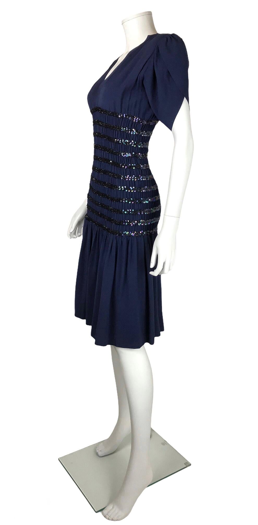 SAINT LAURENT Rive Gauche, 1983. 
Crepe de chine cocktail dress embroidered with sequins. Smocked waistline that sculpts the figure from the bust to the hips. Reinforced structuring shoulders. Small sewing made in the neckline visible in