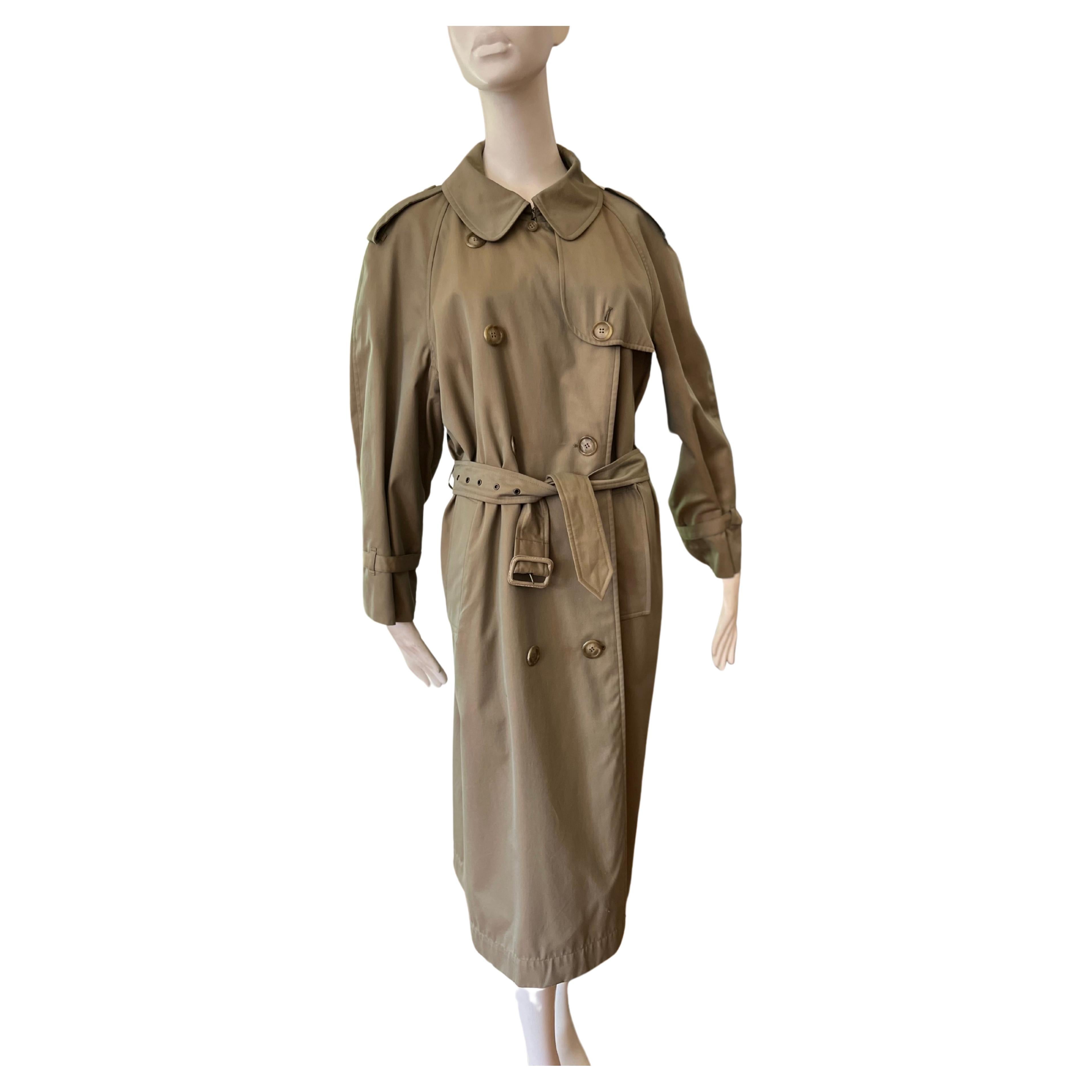 This is a classic Yves Saint Laurent 1980s cotton trench coat. The color is a luminescent green; it is double breasted; has side slit pockets; leather cuffs mini belts; epaulettes; a nice pleat at the back, and a cape effect. 
The 2023/24 version is