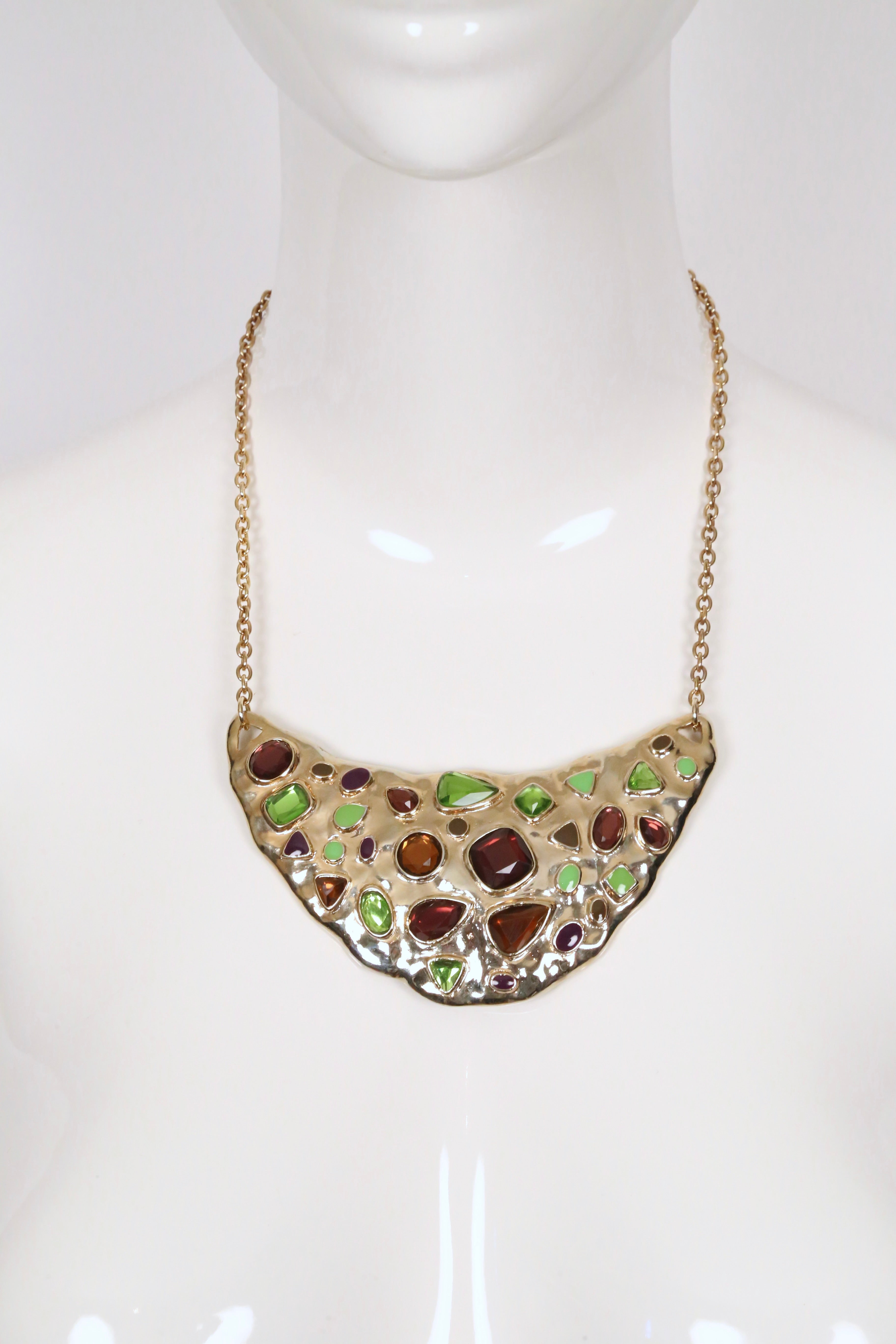 Questa collana di Yves Saint Laurent presenta un ciondolo scultoreo a forma di mezzaluna incastonato in una catena dorata. Il pendente è intarsiato con cabochon di vetro di forma irregolare in ricche tonalità Jewell - verde vivo, ambra e viola e