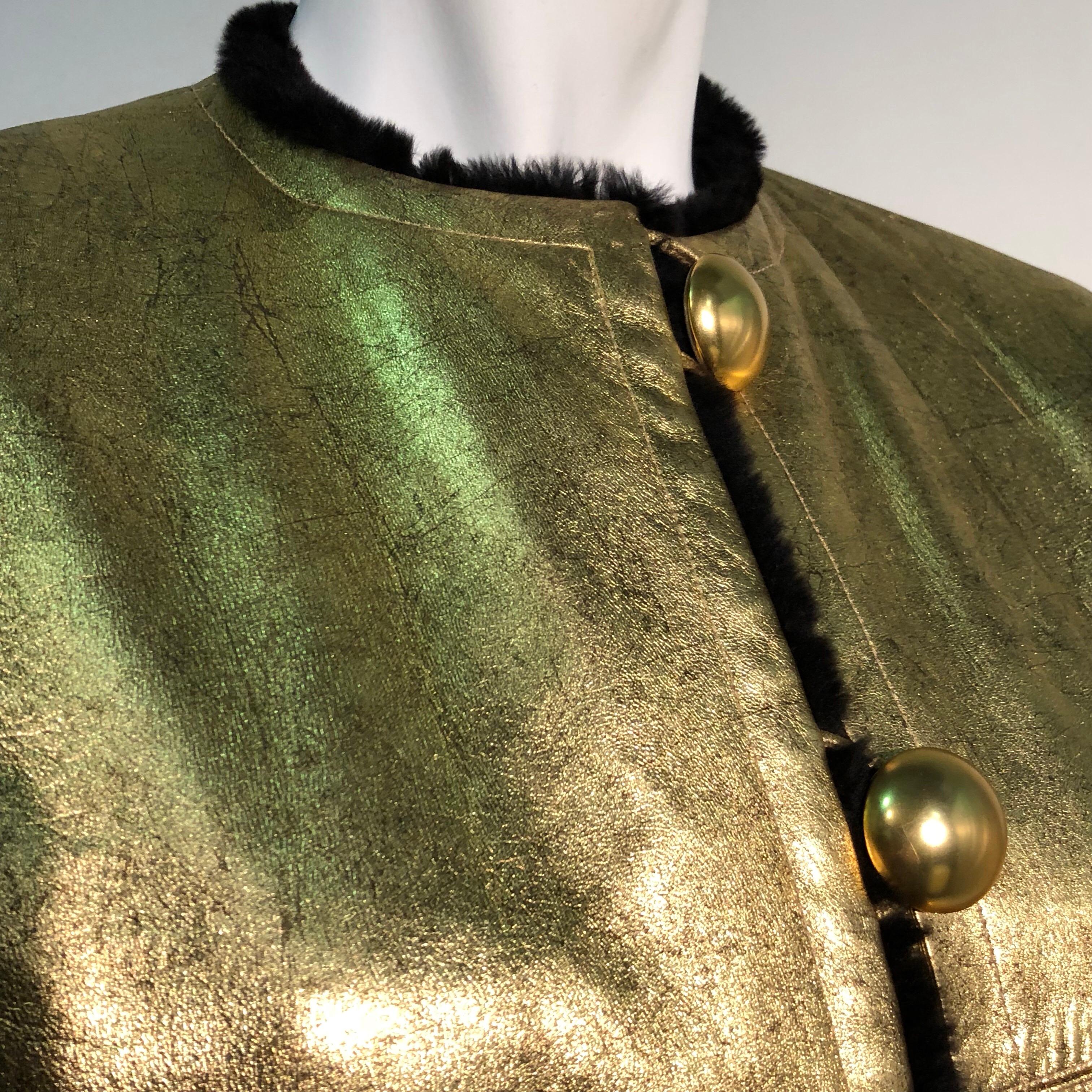 A 1980s Yves Saint Laurent gold leather coat with a luxurious black sheared fur lining. Collar-less with large gold-tone dome topped buttons down front. Structured padded shoulders. A rare beauty and one-of-a-kind special order of it’s time.
.
Size