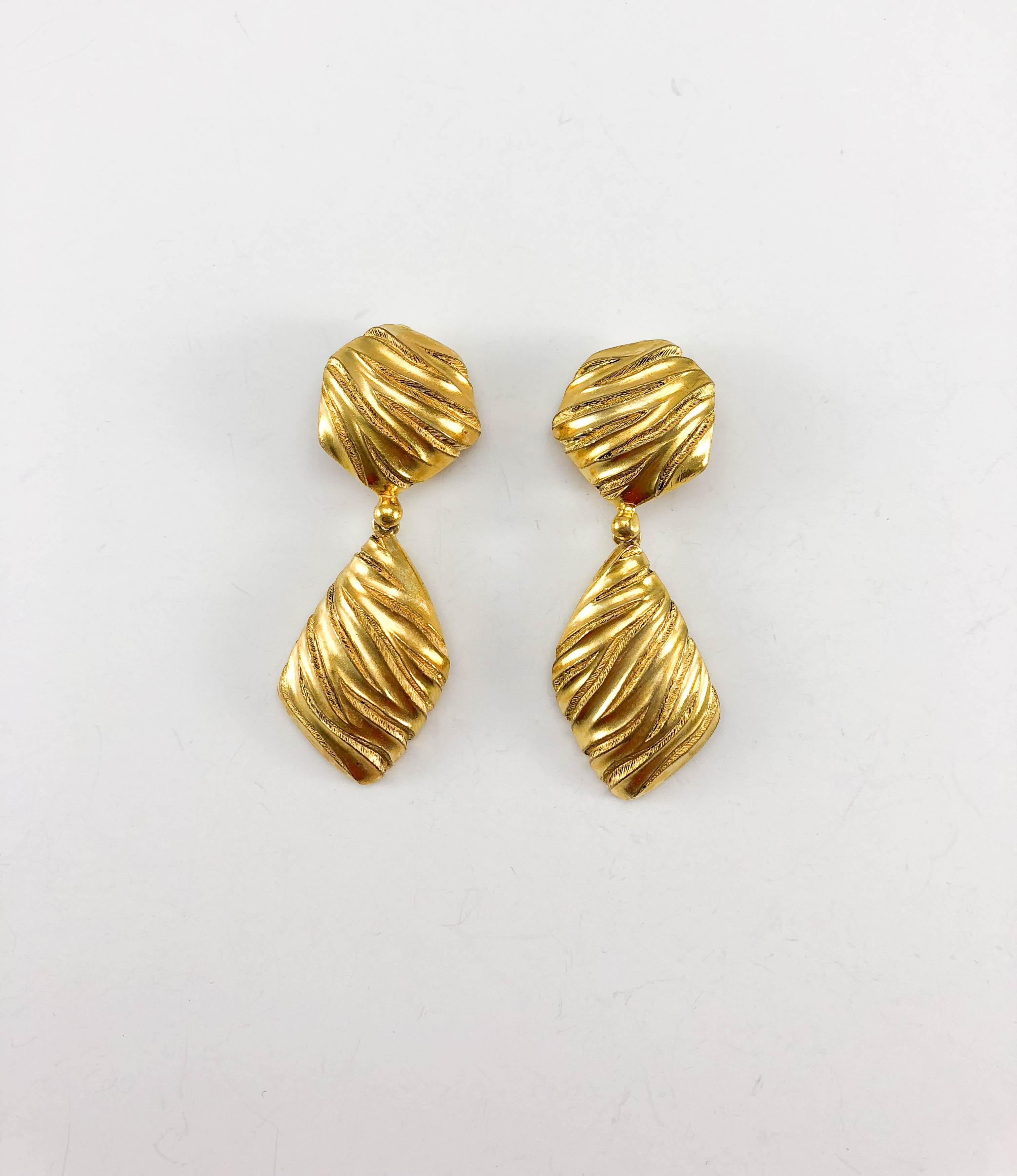 Vintage Yves Saint Laurent Gold-Plated Ribbed Dangling Earrings. These striking earrings by Yves Saint Laurent date back from the 1980’s. Made in gold-plated metal, the ribbing is animal-print inspired. YSL signed on the back. Bold, yet elegant,