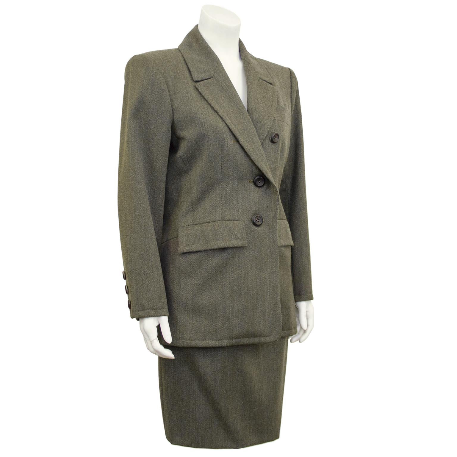 1980s Yves Saint Laurent Rive Gauche khaki wool skirt suit. Jacket features shoulder pads that create a strong, statement shape. Jacket is slightly asymmetric with two middle and lower functioning buttons. Two flap pockets and slit breast pocket