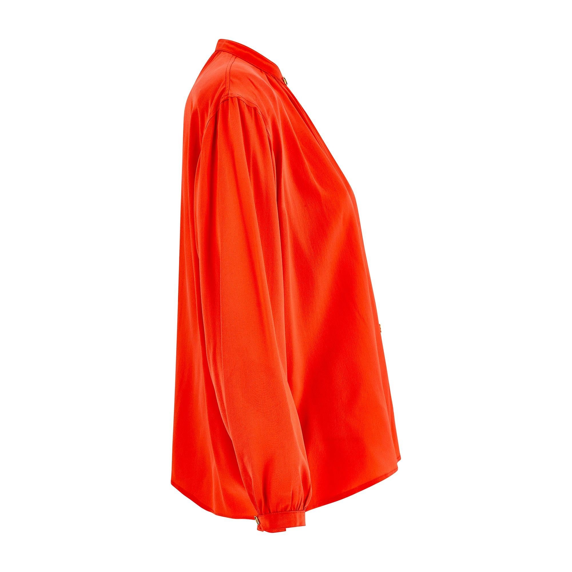 This timeless silk shirt was designed by French fashion house Yves Saint Laurent during the 1980s but could conceivably be a bit later, say early 1990s. Made in France, it is crafted from matte silk in vibrant tangerine orange. The label reads