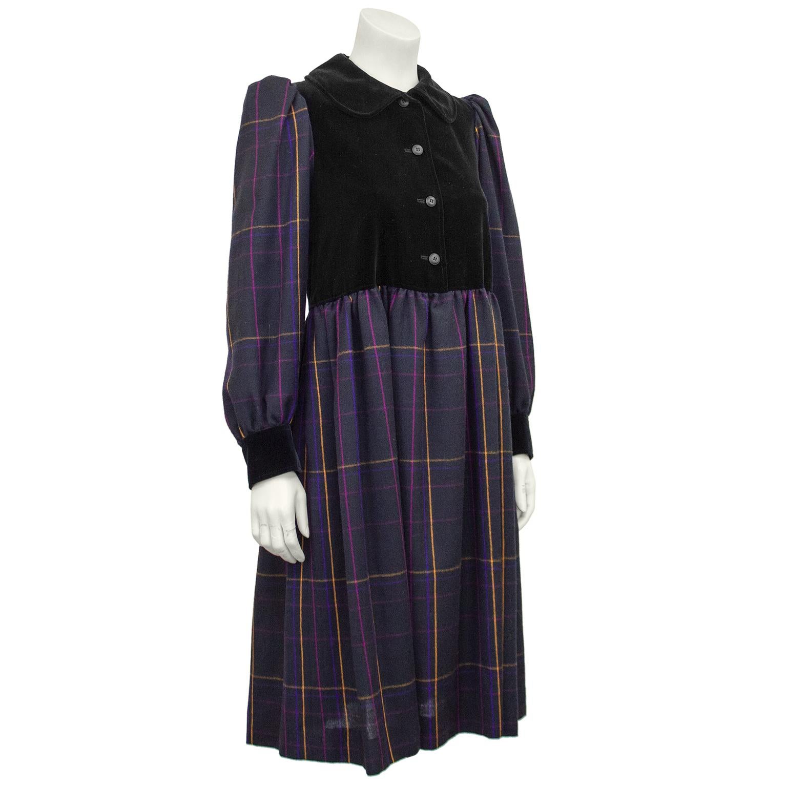1980s Yves Saint Laurent Rive Gauche peasant style shirt dress. Black velvet bodice with a large peter pan collar and black buttons. Long bishop sleeves and skirt are charcoal grey and purple wool tartan with accents of pink and yellow. Black velvet