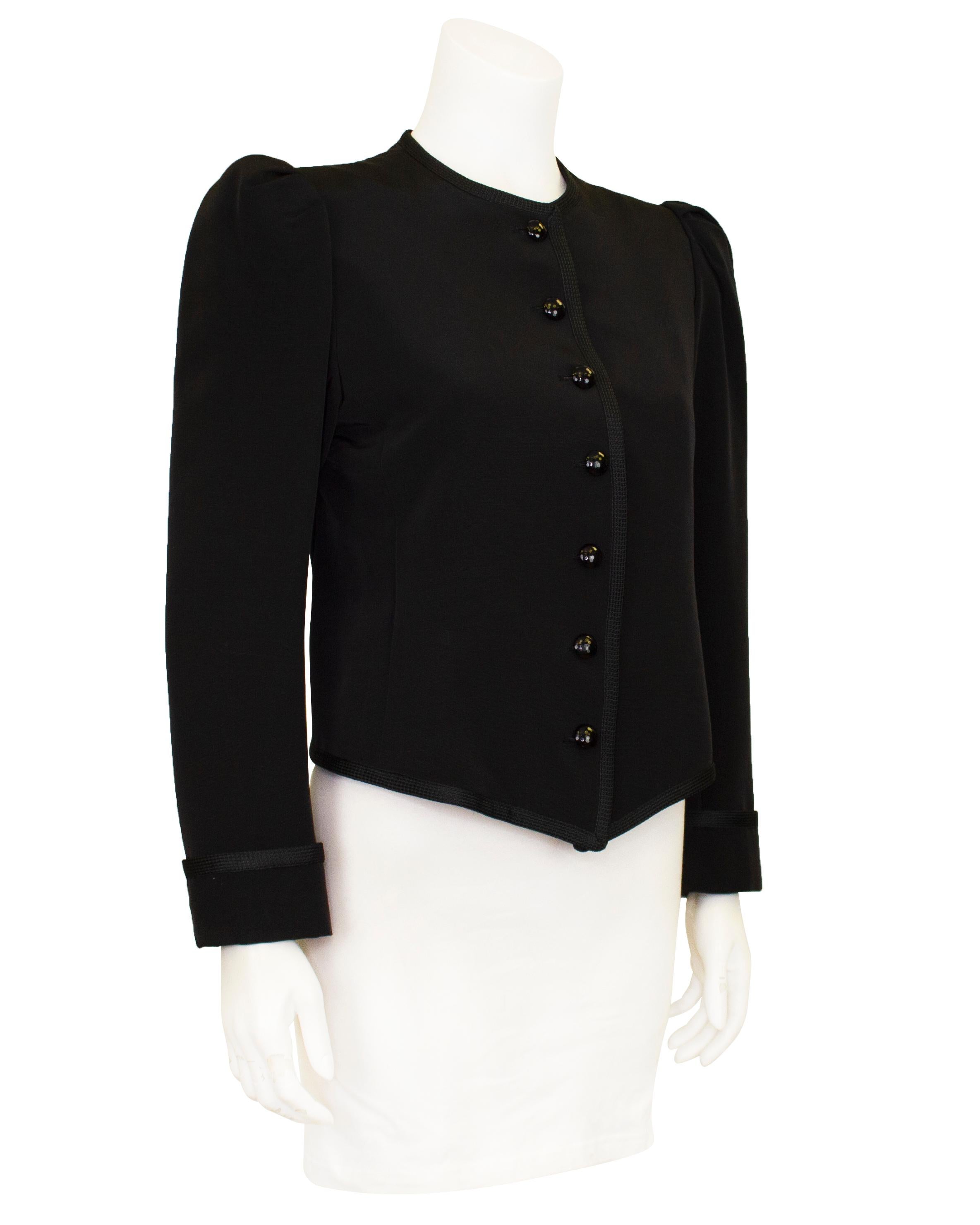 A classic, simple and stunning YSL Rive Gauche jacket from the 1980s. Crafted from a luxurious black cordé with a woven trim. The jacket is collarless with dome shaped buttons that catch the light beautifully. It is slightly fitted through the body