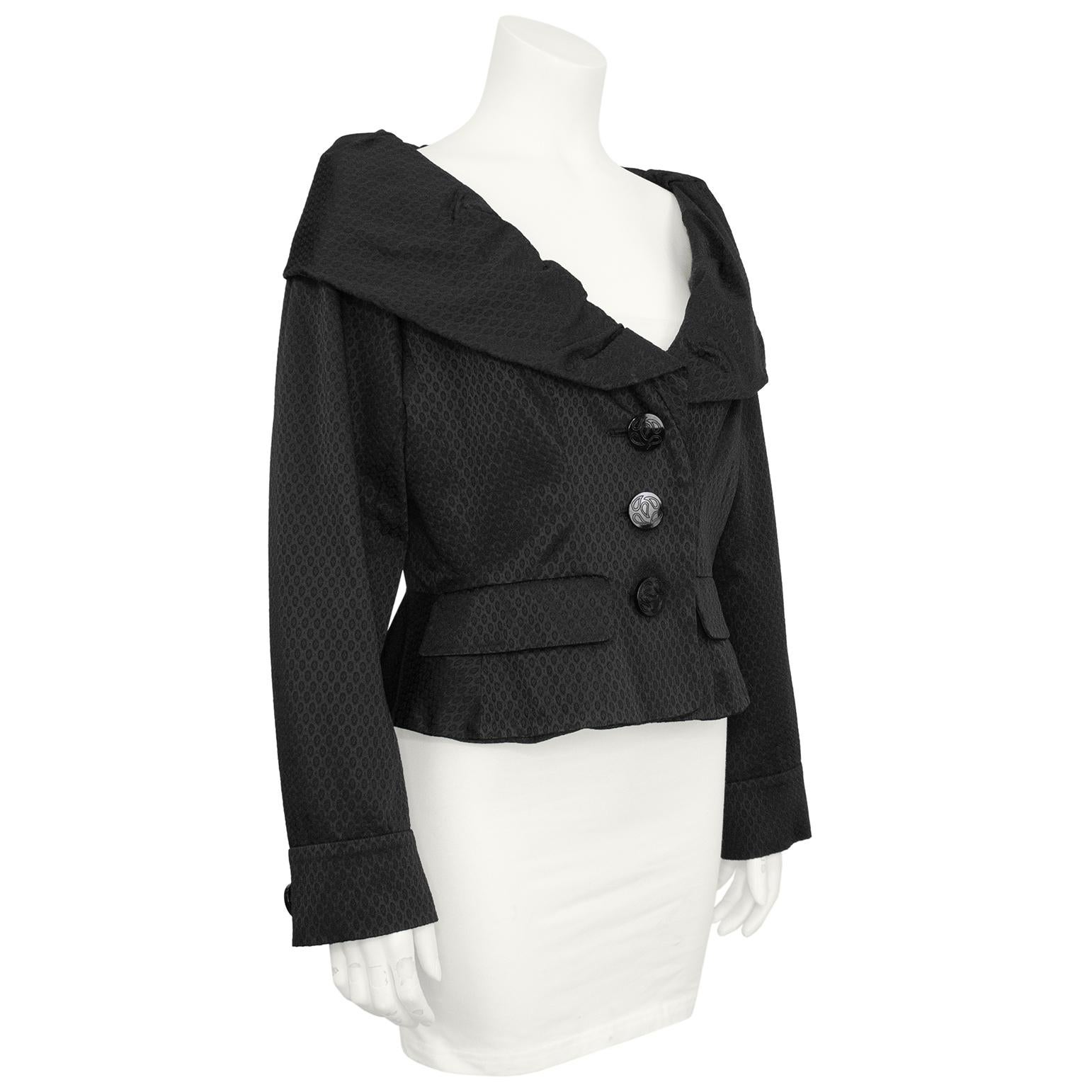 Chaqueta entallada en jacquard negro texturizado Yves Saint Laurent de los años 80, con exagerado cuello redondo fruncido. Cierre delantero de tres botones, dos bolsillos delanteros decorativos, entallado por la cintura con un solo botón  en el puño
