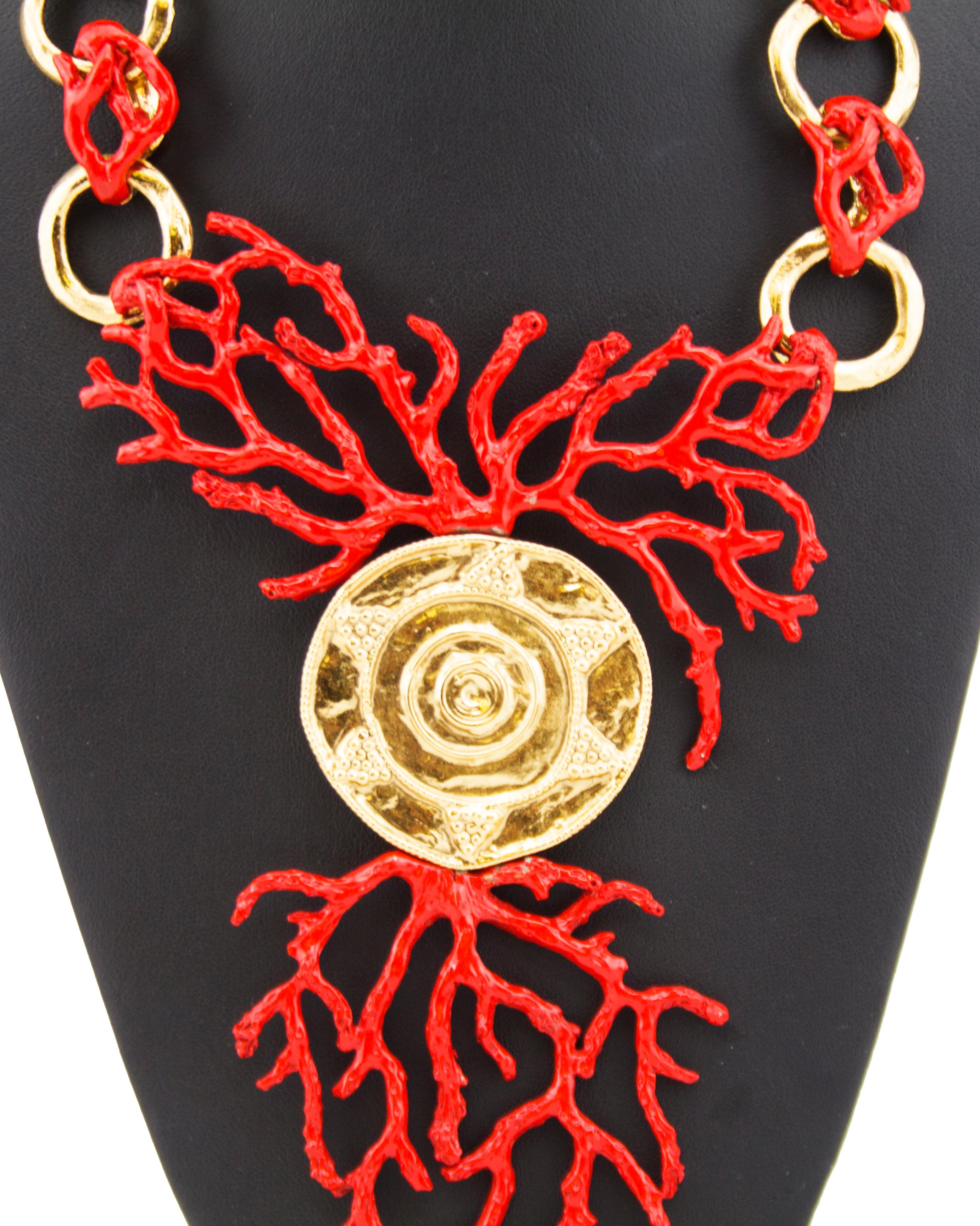 Stunning 1980s Yves Saint Laurent Rive Gauche statement necklace. Gold tone metal with a bright orange-red faux coral enamel details. Large round gold pendant with circular sun details. Gold chain link rings alternate between the smaller coral