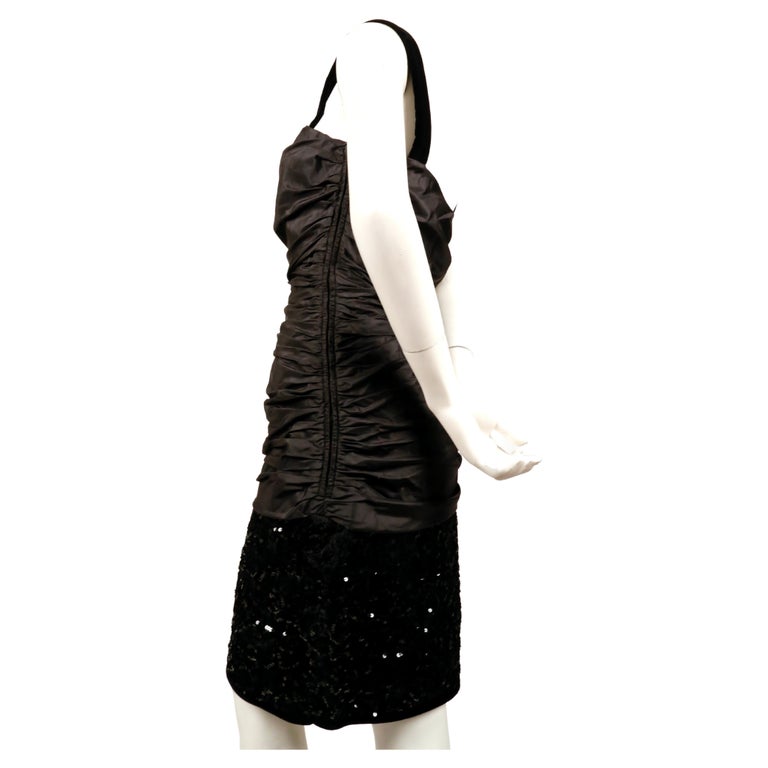 Black, sequined dress with ruched bodice and velvet straps designed by Yves Saint Laurent dating to the 1980's. Labeled a French size 40. Approximate measurements: bust 34