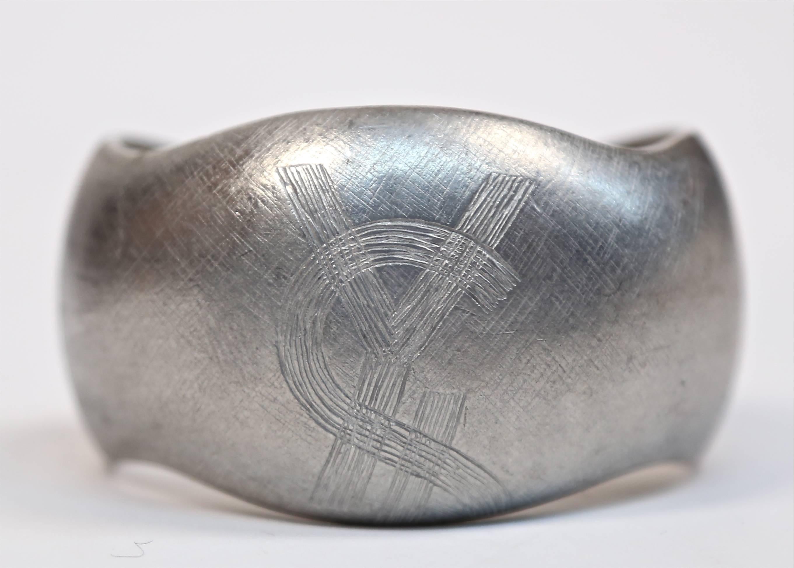 Brushed cuffs in silver toned metal by Yves Saint Laurent dating to 1985. Both bracelets measure approximately 6