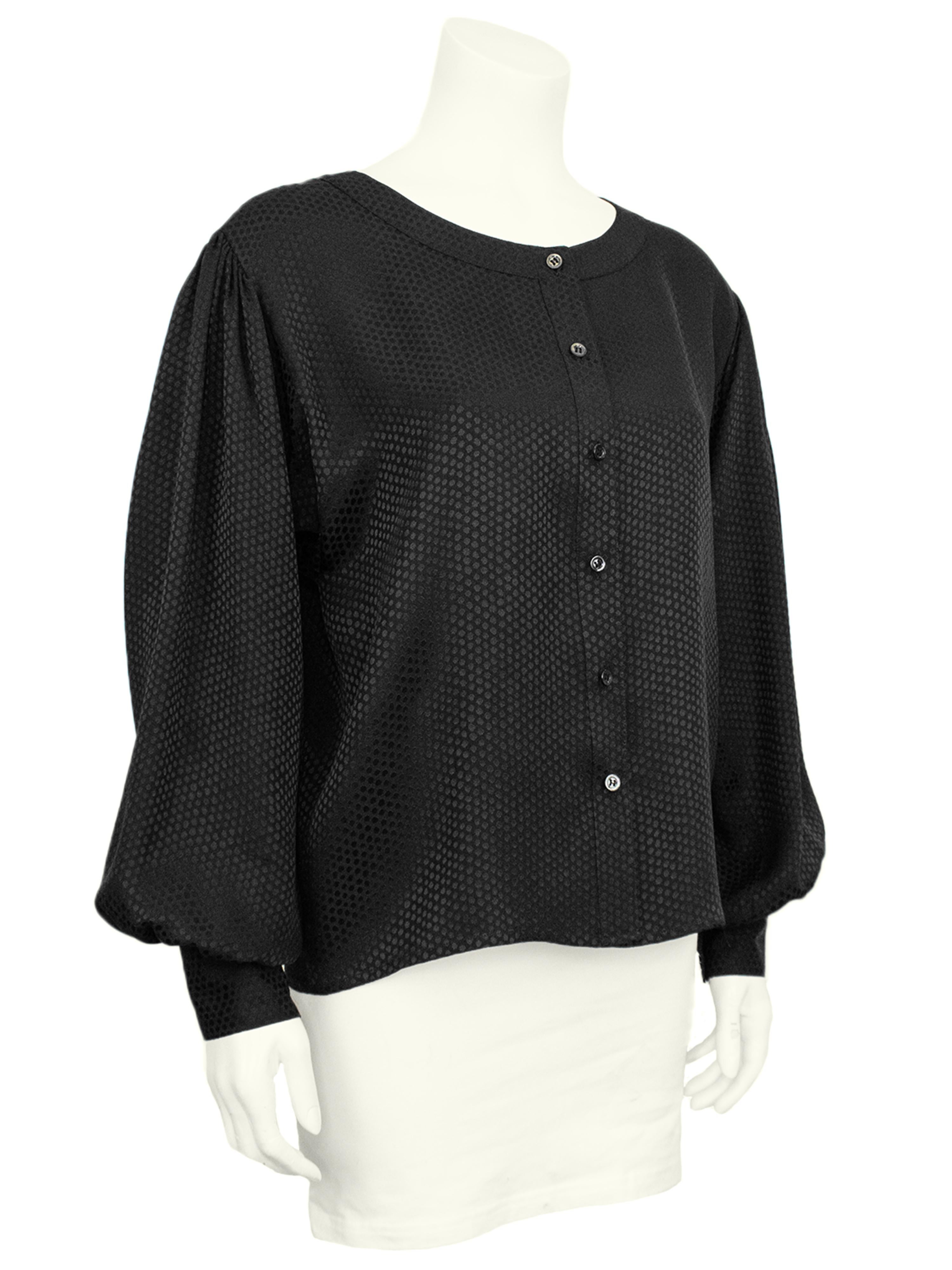 Yves Saint Laurent Rive Gauche blouse from the 1980s made from a silk jacquard with a tonal black on black small polka dot pattern. Collarless with small grey mother of pearl buttons down the centre front. Loose through the body with dolman shaped