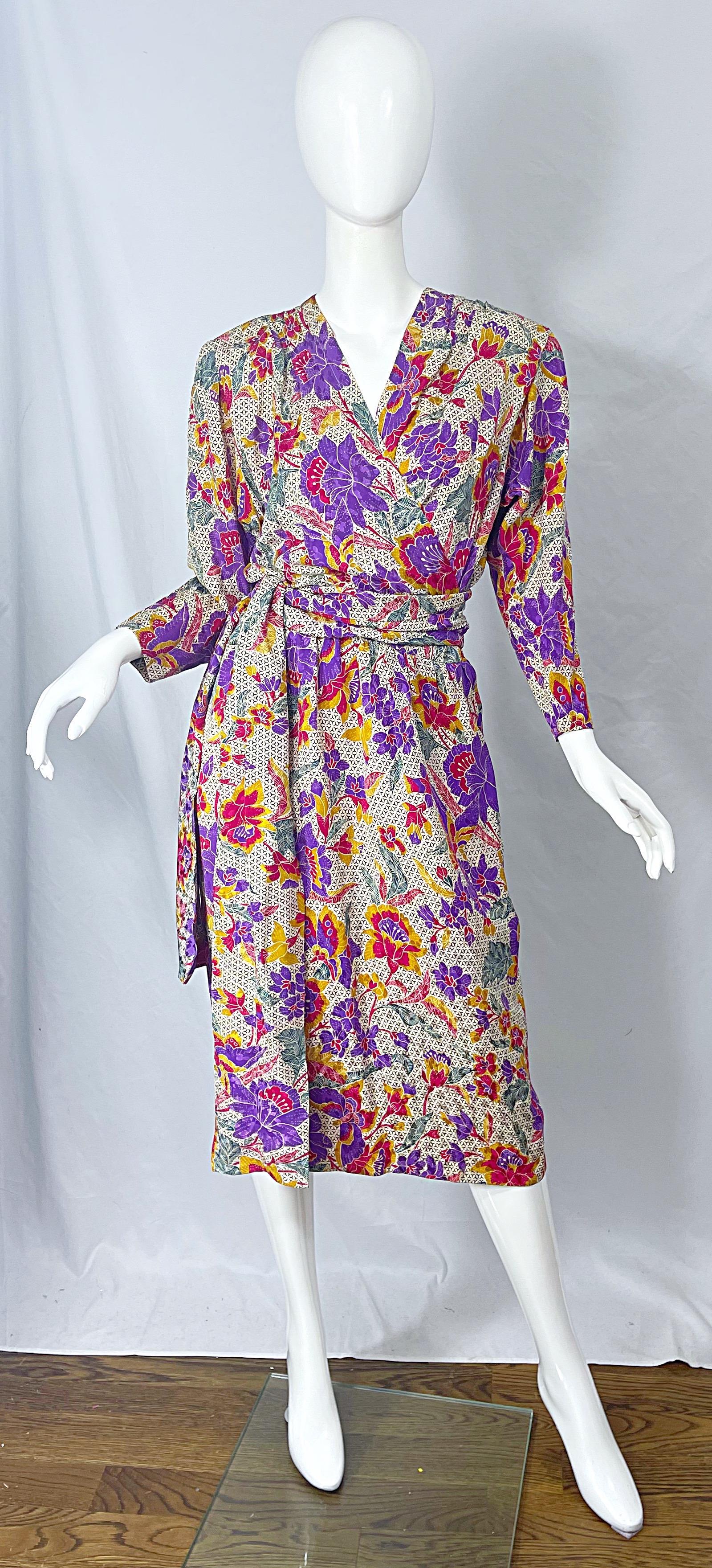 Chic vintage 80s YVES SAINT LAURENT Rive Gauche flower and logo print silk wrap dress ! Features a floral print with vivid colors of purple, marigold, pink, green throughout. Ivory backdrop with the black Y logo printed all over. Pockets at each
