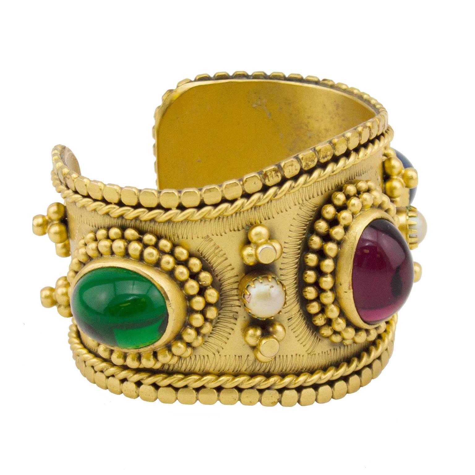 Beautiful 1980s Yves Saint Laurent extremely detailed gold tone cabochon cuff. Poured glass stones in green, red and blue and two small faux pearls. Stunning attention to detail that catches the eye immediately. Signed. Excellent vintage condition,