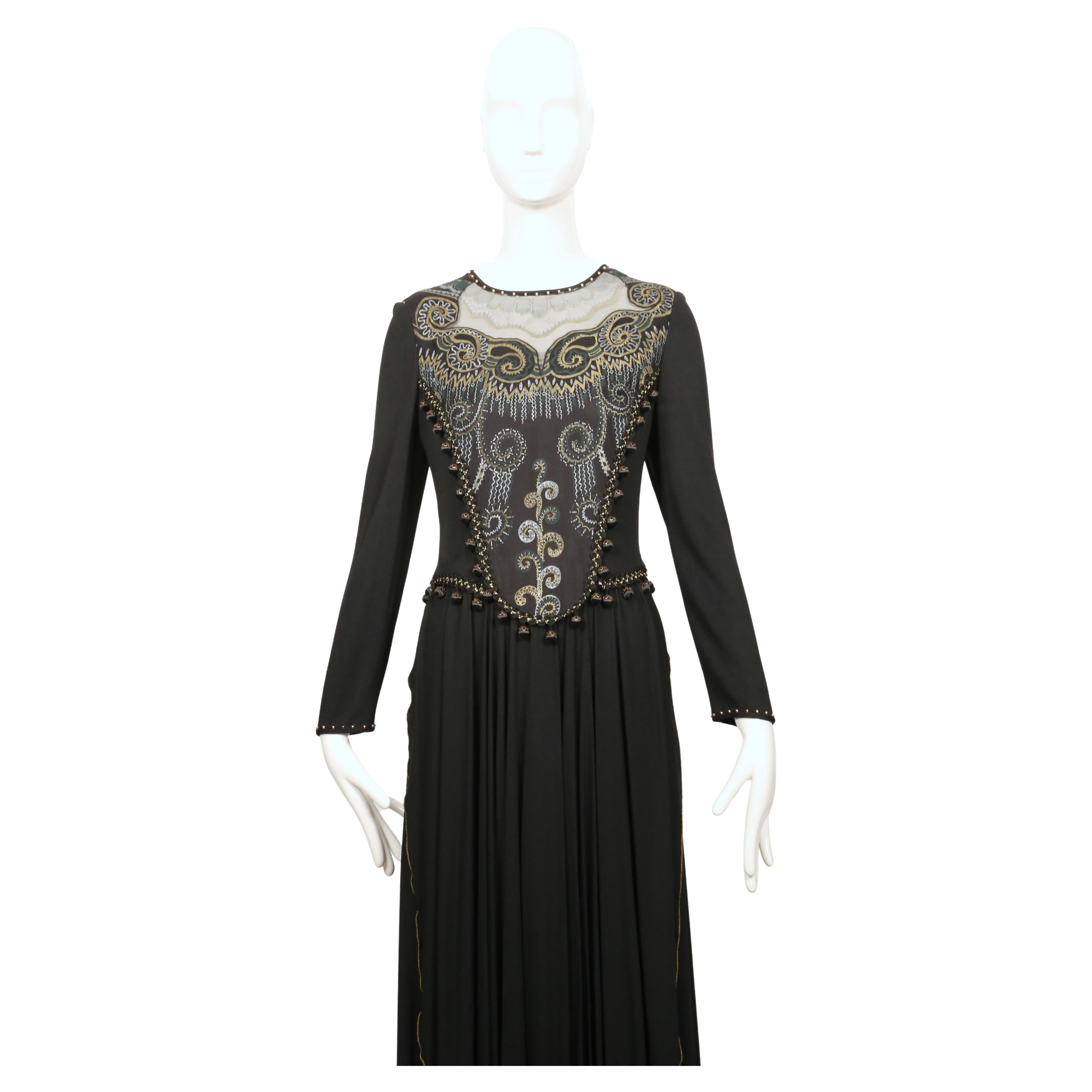 Cette robe Zandra Rhode combine un doux jersey noir avec de la soie peinte à la main travaillée dans le corsage. Le panneau peint se pose sur une encolure transparente et est encadré de petits pompons perlés qui se prolongent autour de la taille et