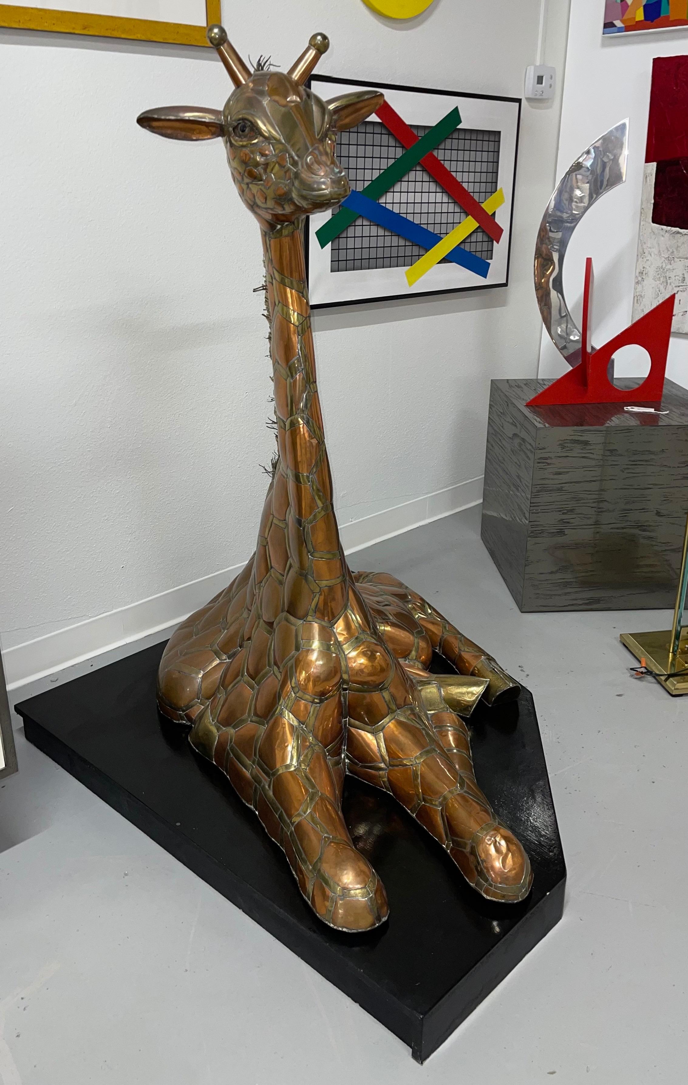 A beautiful large Giraffe brass and copper sculpture by Sergio Bustamante purchased in 1981. It is seated on a wood base painted black. The sculpture comes with a copy of a receipt dated April 25, 1981. In good age appropriate condition with some