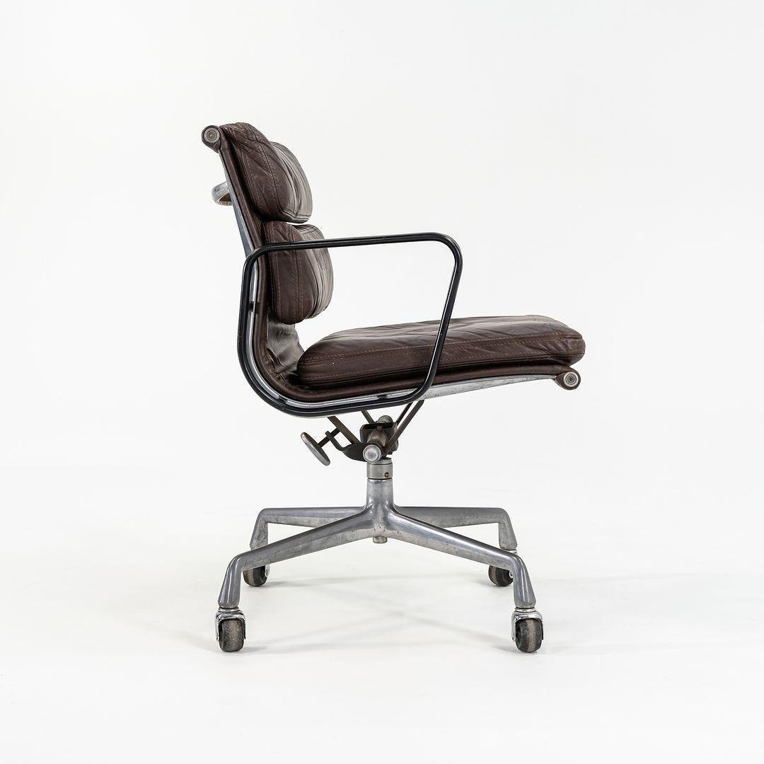 This is an Eames Aluminum Group Soft Pad Management Chair, Model EA148, designed by Charles and Ray Eames for Herman Miller in 1969. This example dates to around 1981. The piece features a cast aluminum frame, and it is upholstered in a brown
