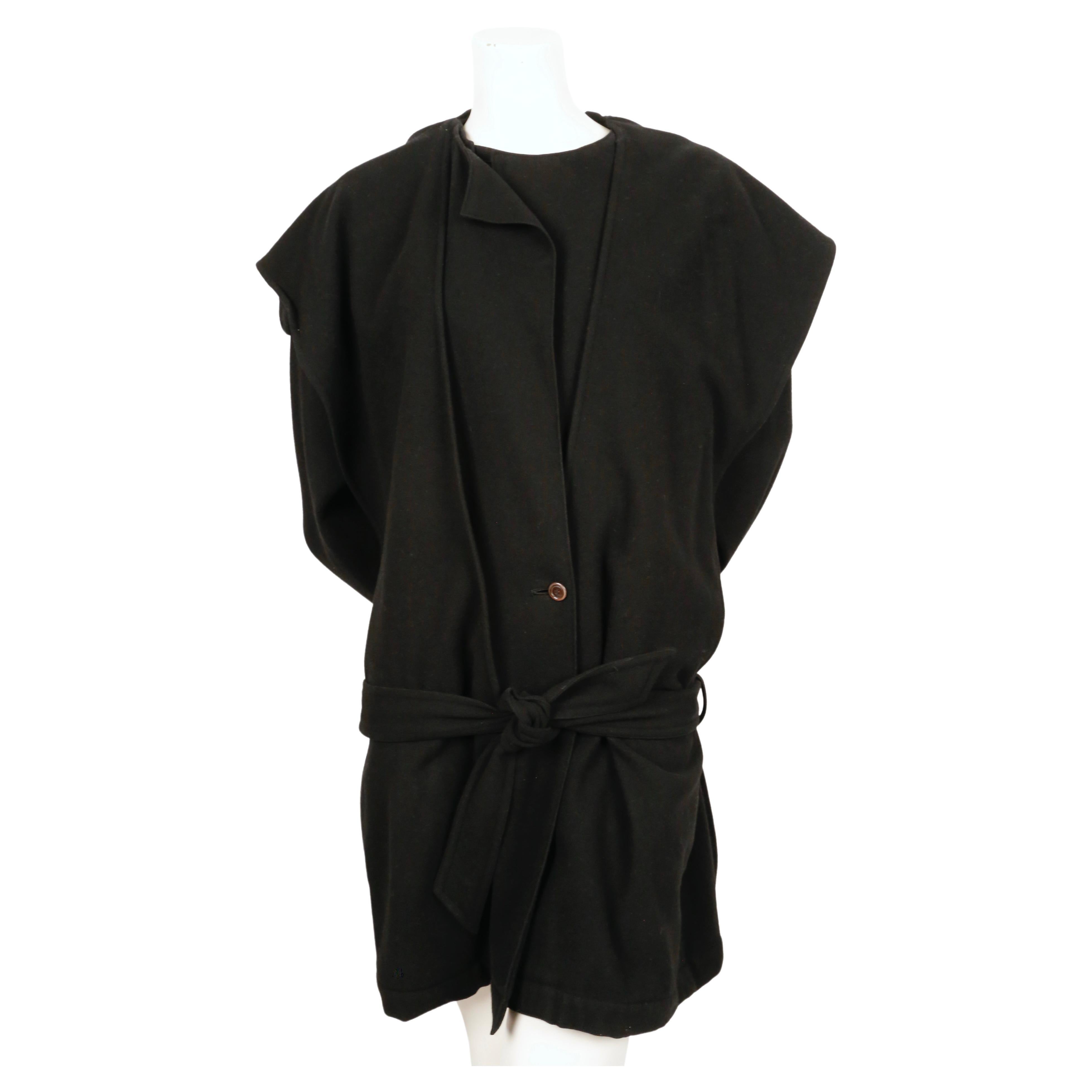 Black wool coat with a draped hood and low waist tie designed by Issey Miyake dating to the 1981 exactly as seen worn by Iman on the runway. Coat has a very unique cut to it. Size 'M'. Approximate measurements: drop shoulder 22