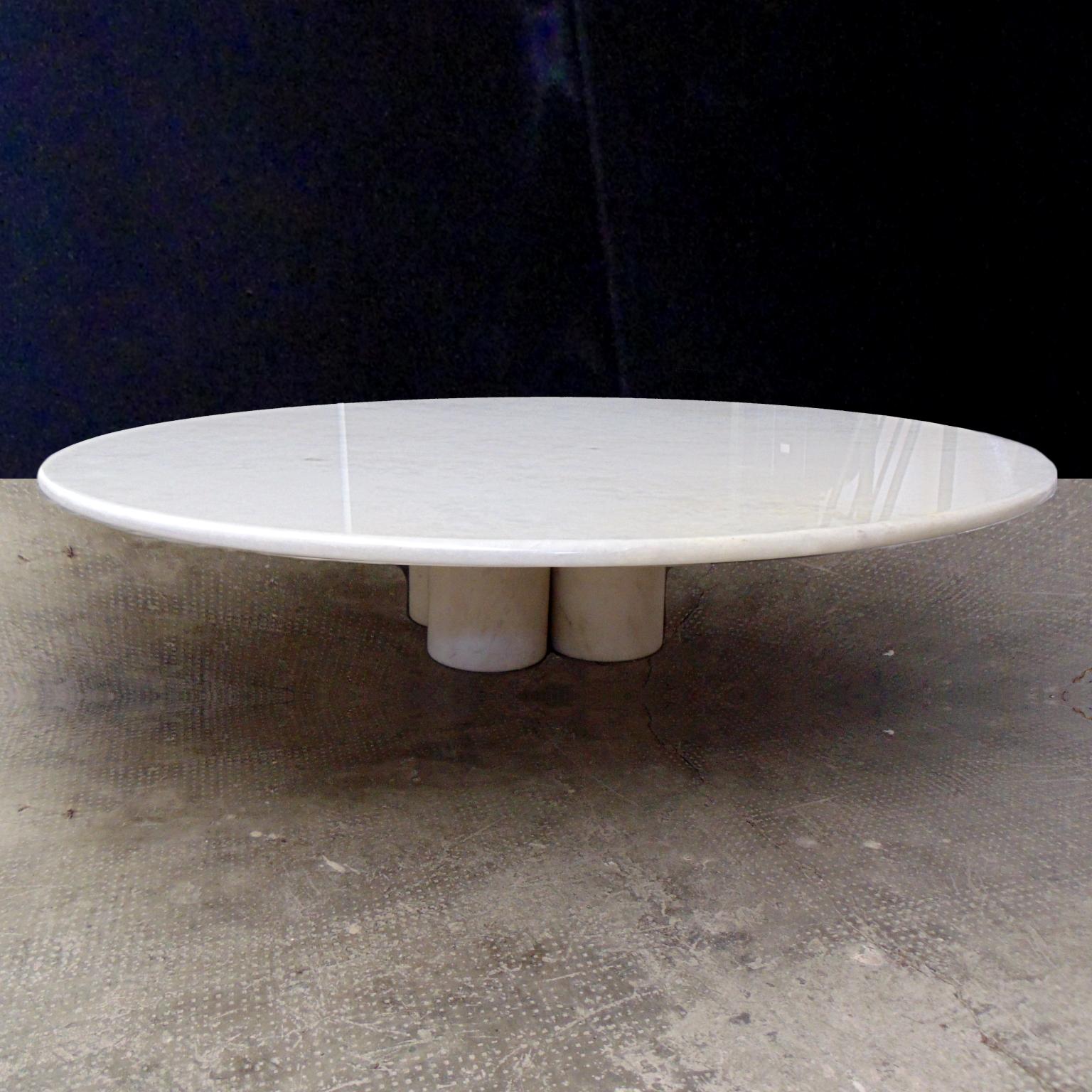 This white marble table (bianco neve of the Brescia area, Italy) has a round top, with rounded-up edge and four cylindrical legs with the upper part as a cone. The white marble is a quite precious type, of extreme clarity and with crystal