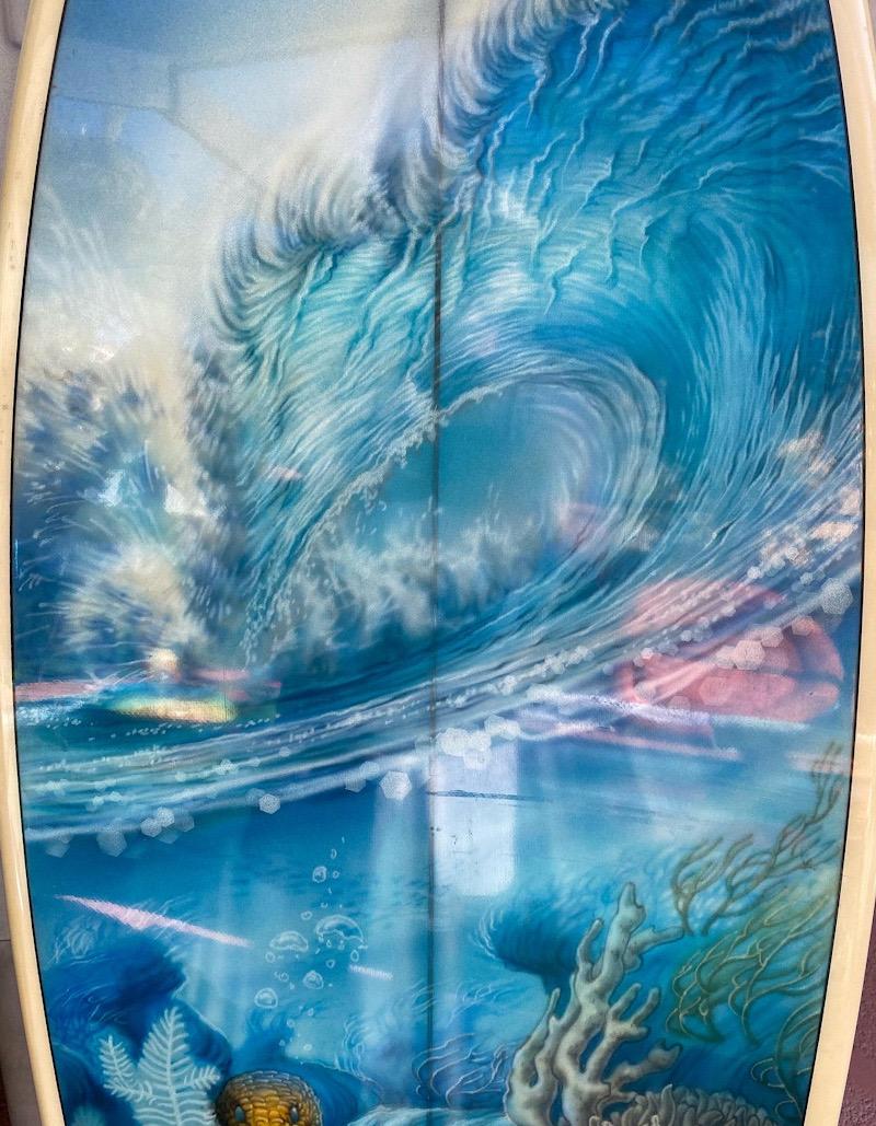 1981 M.T.B. twin-fin surfboard made in 1981 by shaper Johnny Lucas. Features a double-wing round pintail shape-design with magnificent full length airbrushed wave mural masterpiece by the renowned artist, Phil Roberts. Elaborate wave