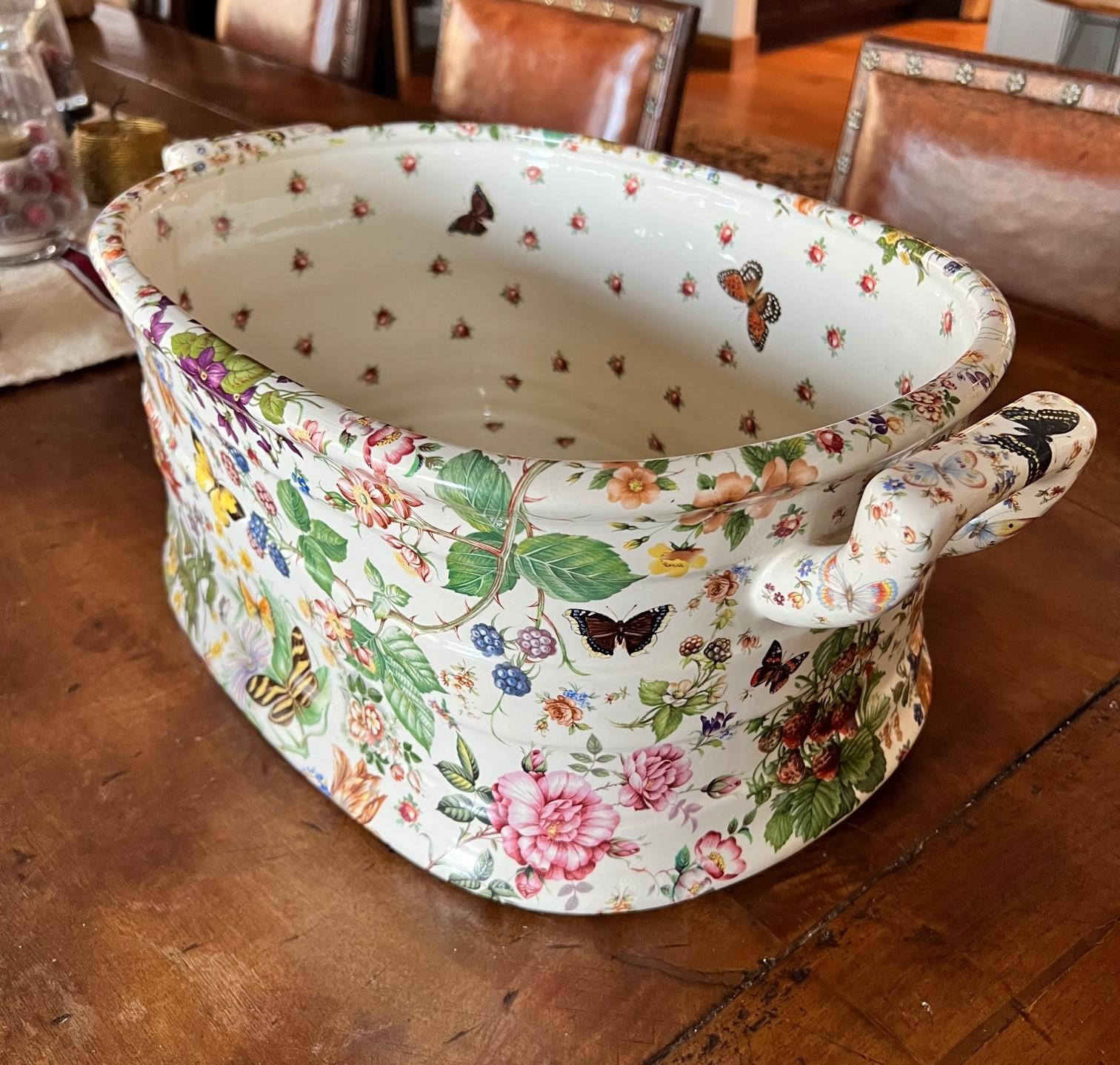 Porcelain foot bath extensively decorated with flora and fauna. The outside is decorated with strawberry plants, flowers, birds and butterflies. The inside is more sparsely decorated with butterflies along the sides and flowers on the base. The