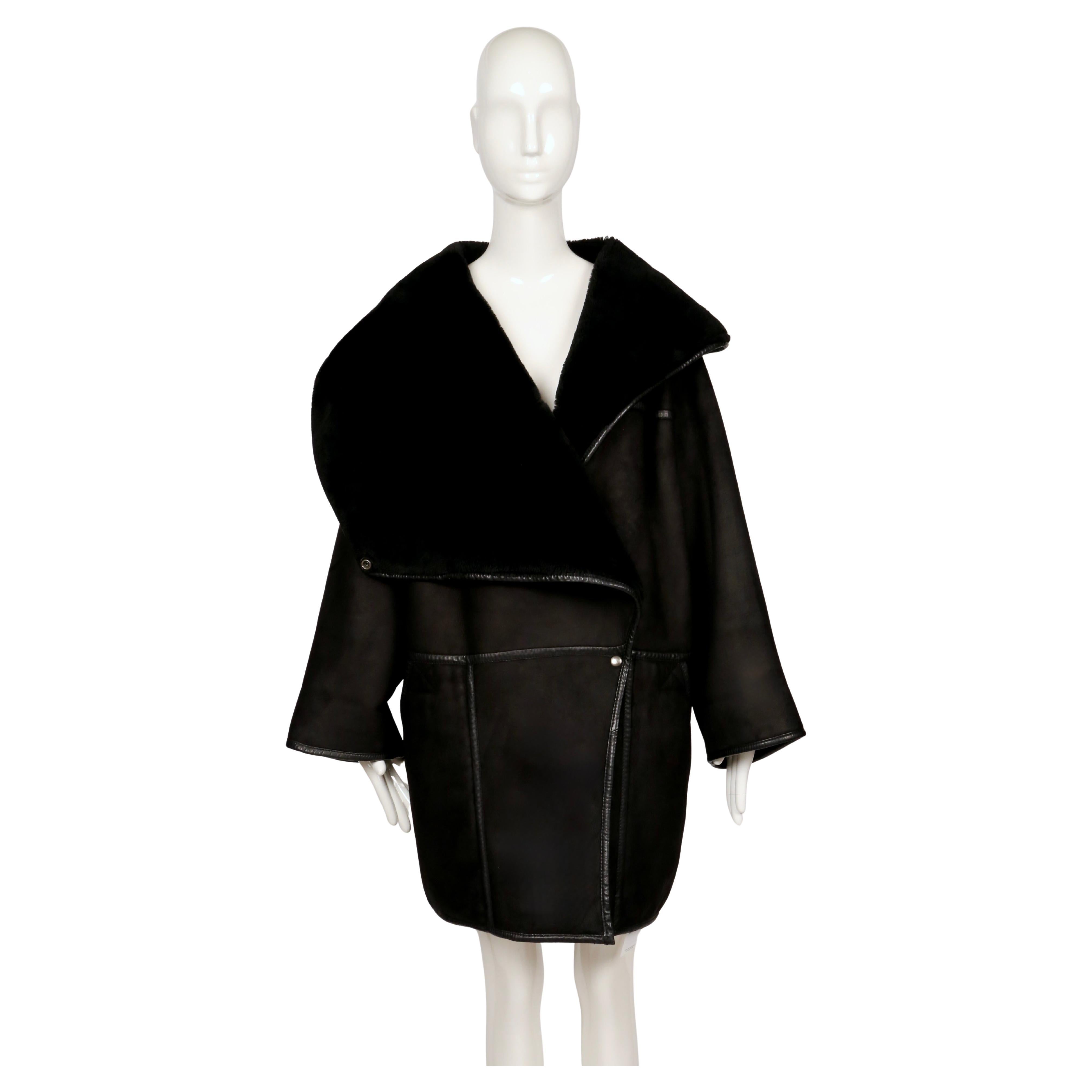 Un cappotto scultoreo in shearling nero della collezione Autunno/Inverno 1982 di Anne Marie Beretta. Tagliato nel suo caratteristico stile architettonico, il capo presenta una silhouette oversize con un drammatico collo a scialle che può essere