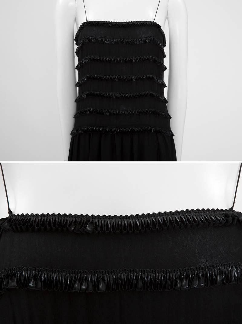 One of a kind 1983 Chanel evening dress dating from Karl Lagerfeld’s debut with the iconic couture house. Constructed in the most refined black silk chiffon, the gown is embellished with satin loop ribbon trim at the bodice and the bottom. Fully