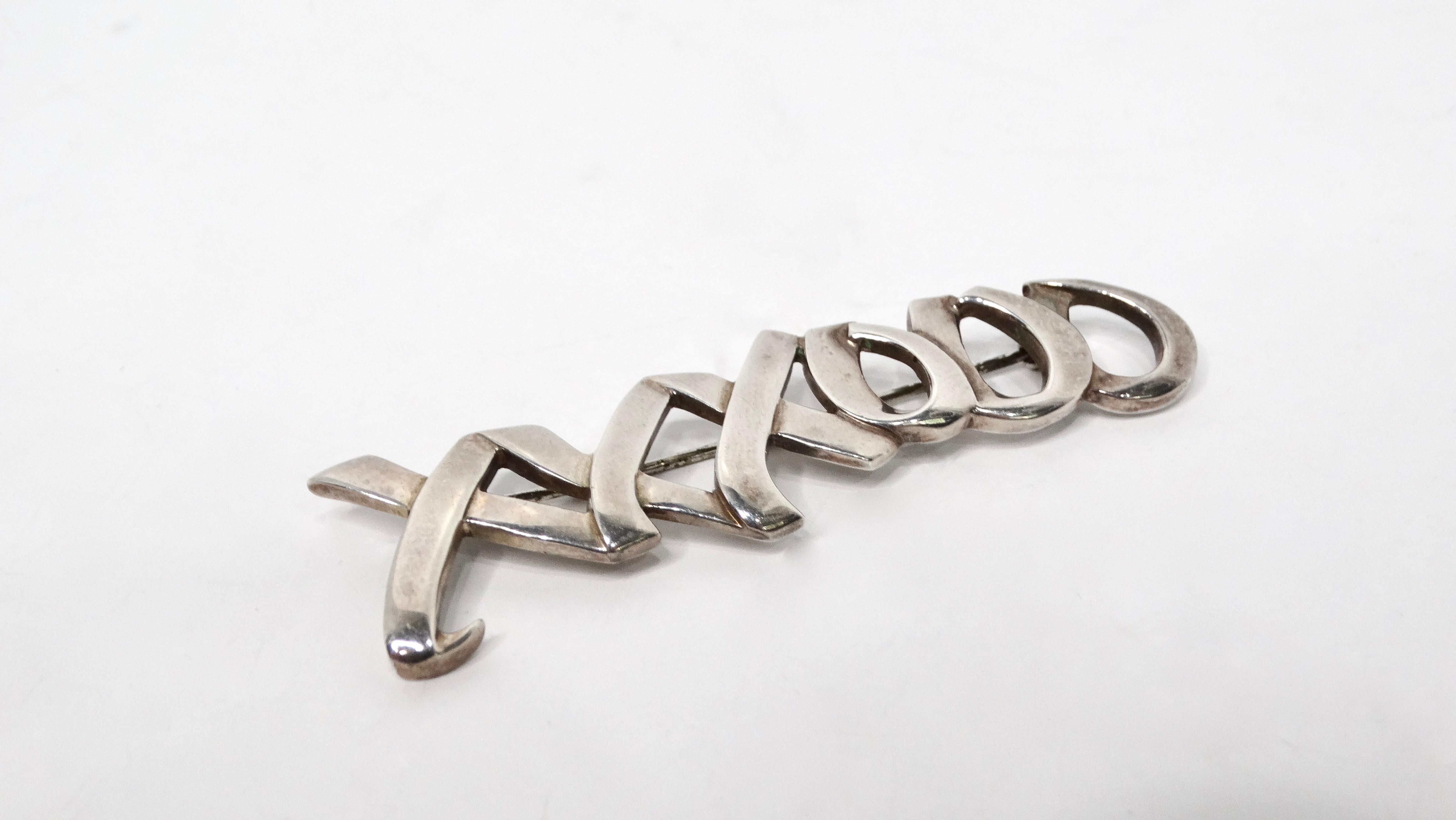 Il modello Paloma Picasso for Tiffany & Co. del 1983. La spilla in argento Sterling Kisses & Hugs è un pezzo senza tempo che incarna l'affetto e la maestria artigianale. Caratterizzata dall'iconico motivo 