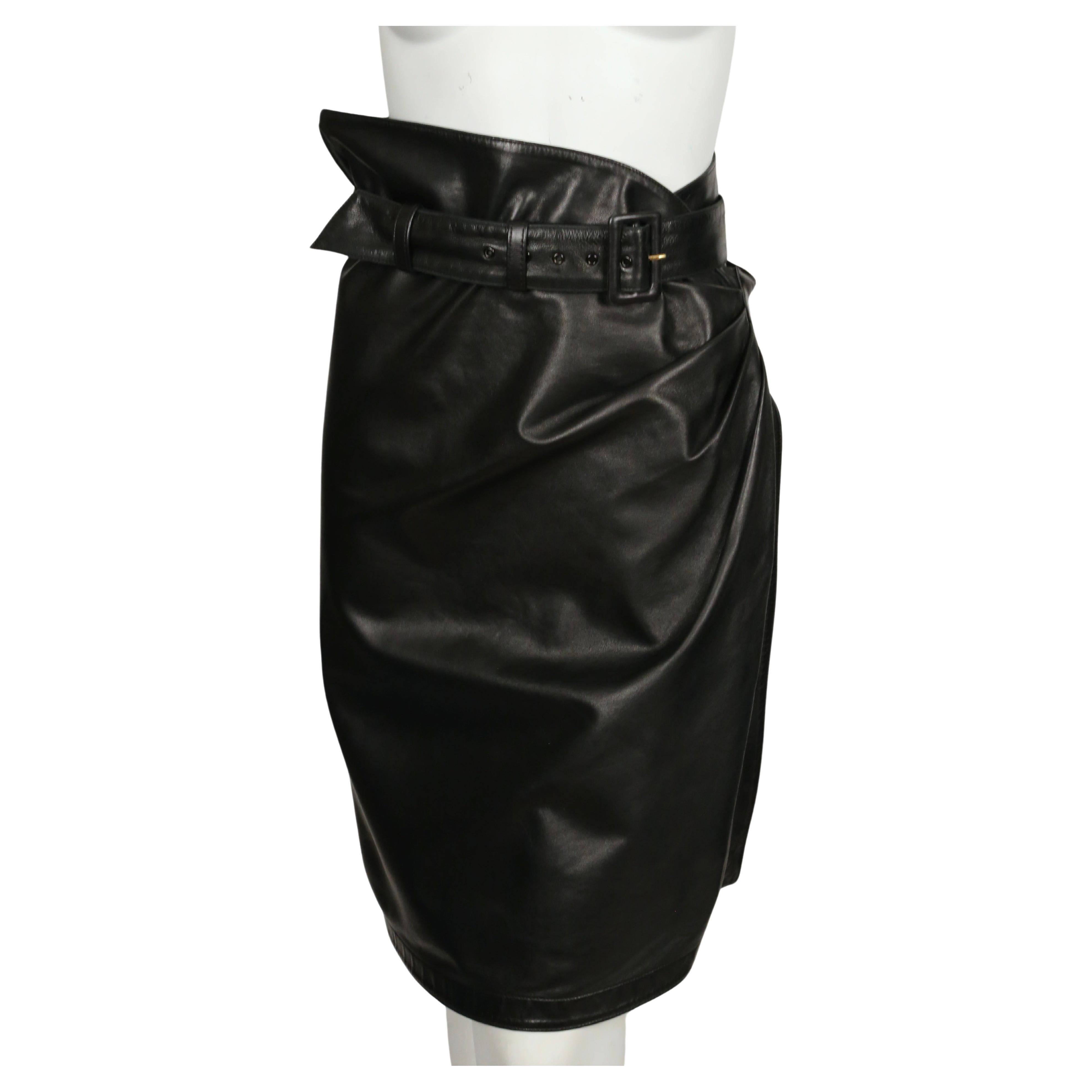 Black, butter-soft lambskin leather skirt with ruching, wrap closure and buckle detail from Azzedine Alaia dating to 1984. No size is labeled however this skirt best fits a U.S. size 6.  Skirt was photographed on a size 2 mannequin who measures 24