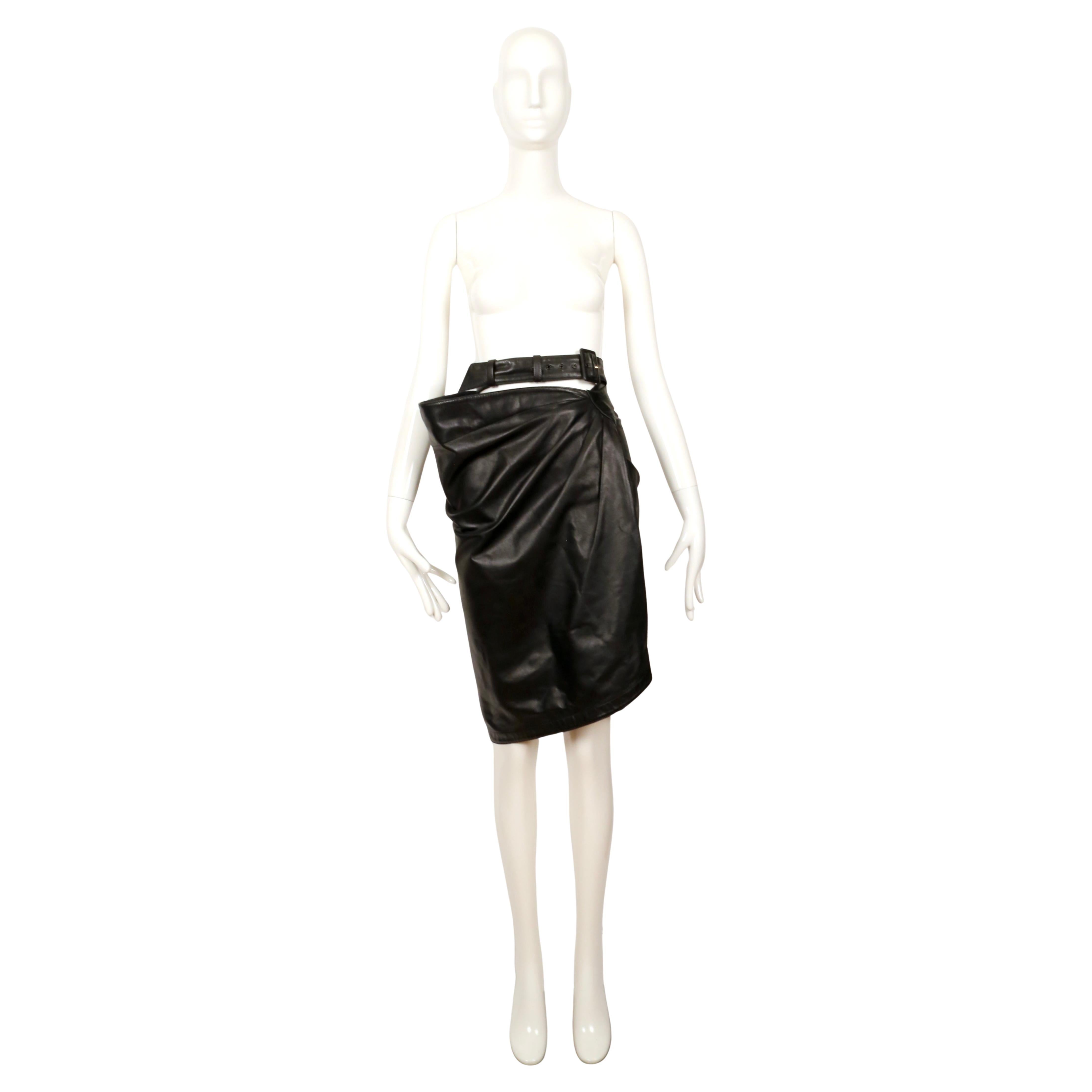 Black, butter-soft lambskin leather skirt with ruching, wrap closure and buckle detail from Azzedine Alaia dating to fall of 1984. A longer version of this skirt was seen on the runway. No size is labeled however this skirt best fits a U.S. size 4