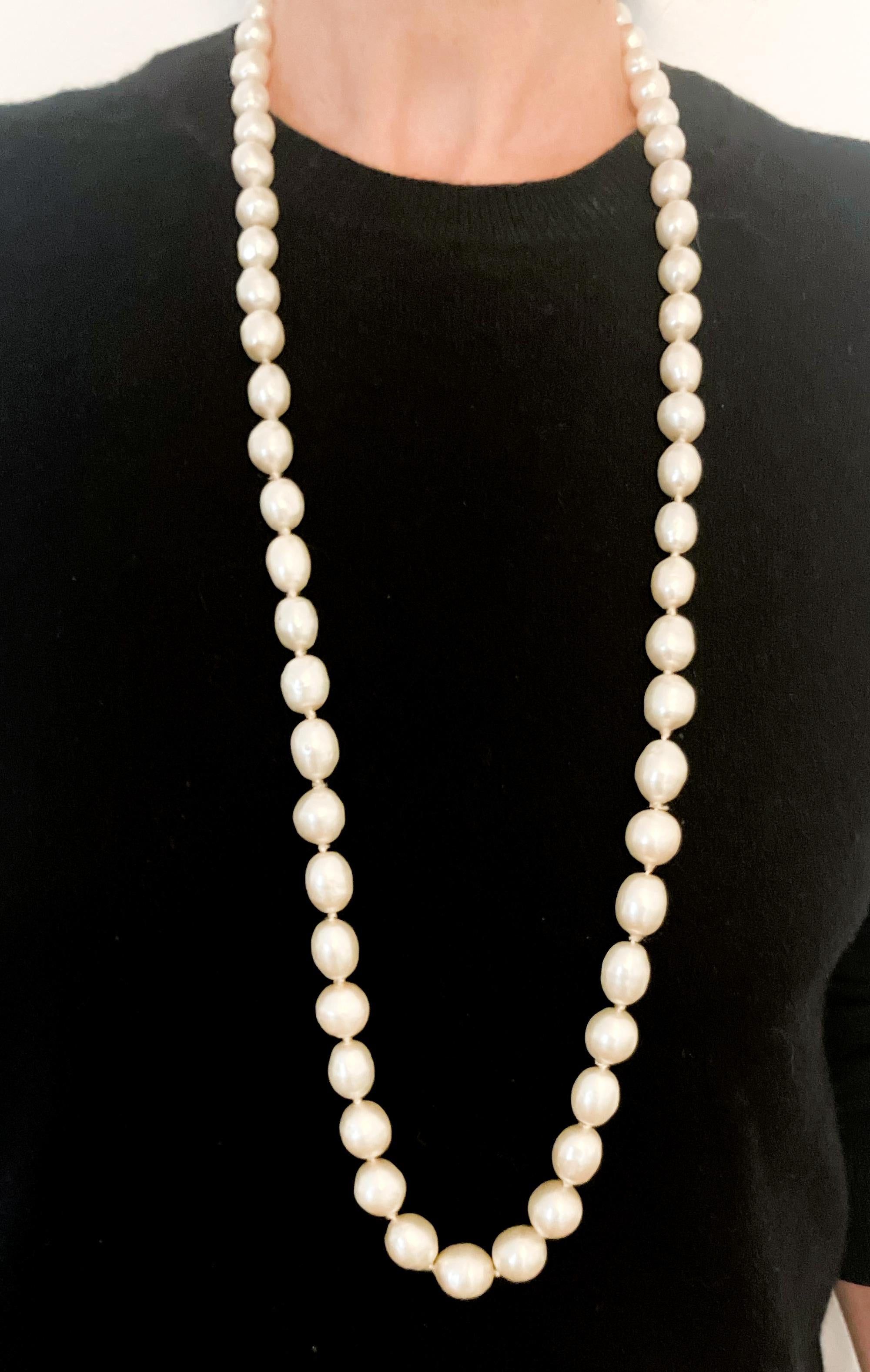 Chanel Elfenbeinfarbenes, langes, unregelmäßiges Kunstperlen-Sautoir-Collier mit langen, großen, unregelmäßigen Kunstperlen und einer goldfarbenen Logoplakette mit Unterschrift. 
Circa 1984 . Hergestellt in Frankreich
Guter Vintage-Zustand.