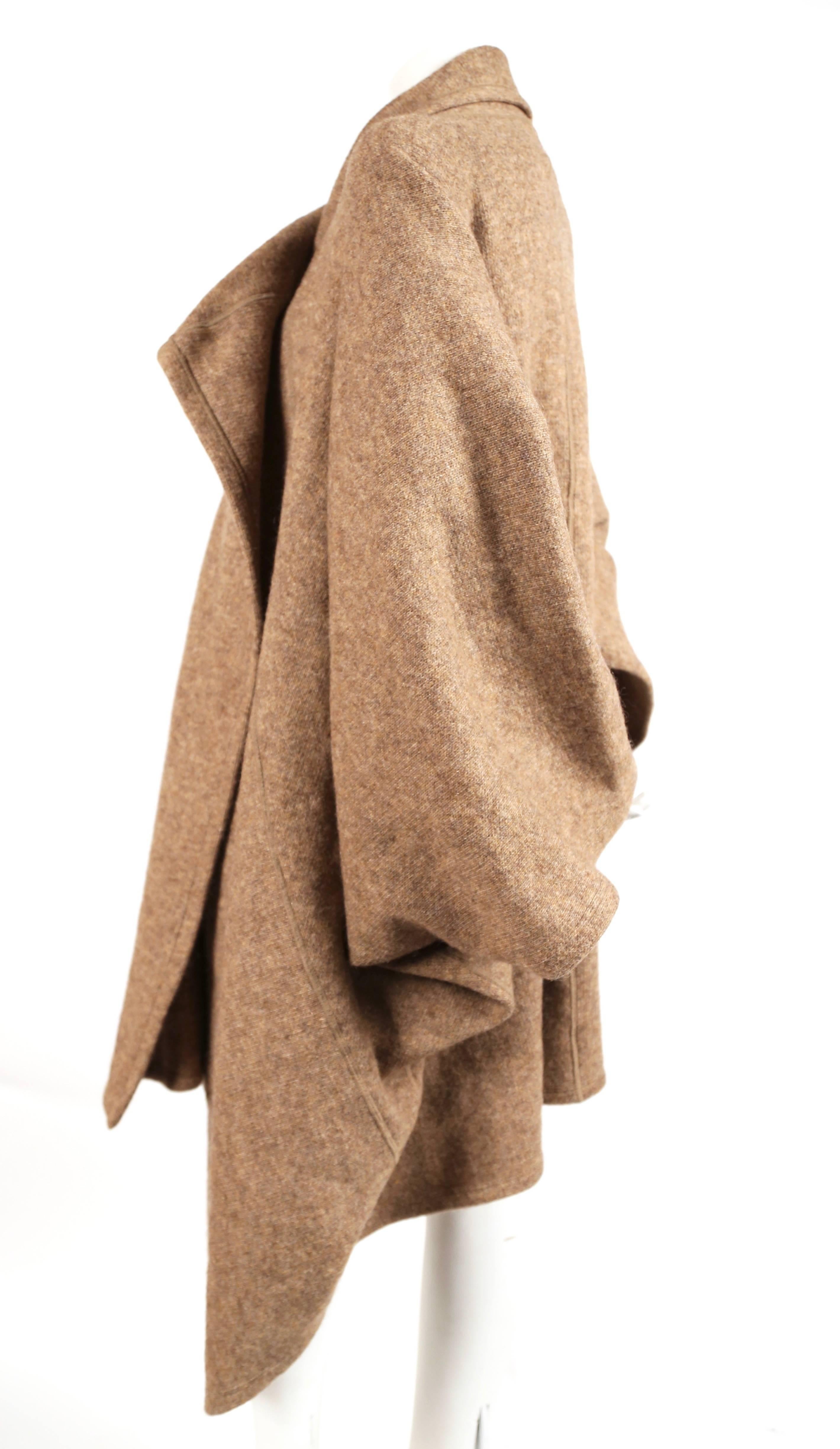 Very rare tan knit wool coat with draped front and pockets from Issey Miyake dating to 1984 exactly as seen on the runway with important provenance. No size indicated however this fits most sizes due to the oversized cut. Photographed on a size 2