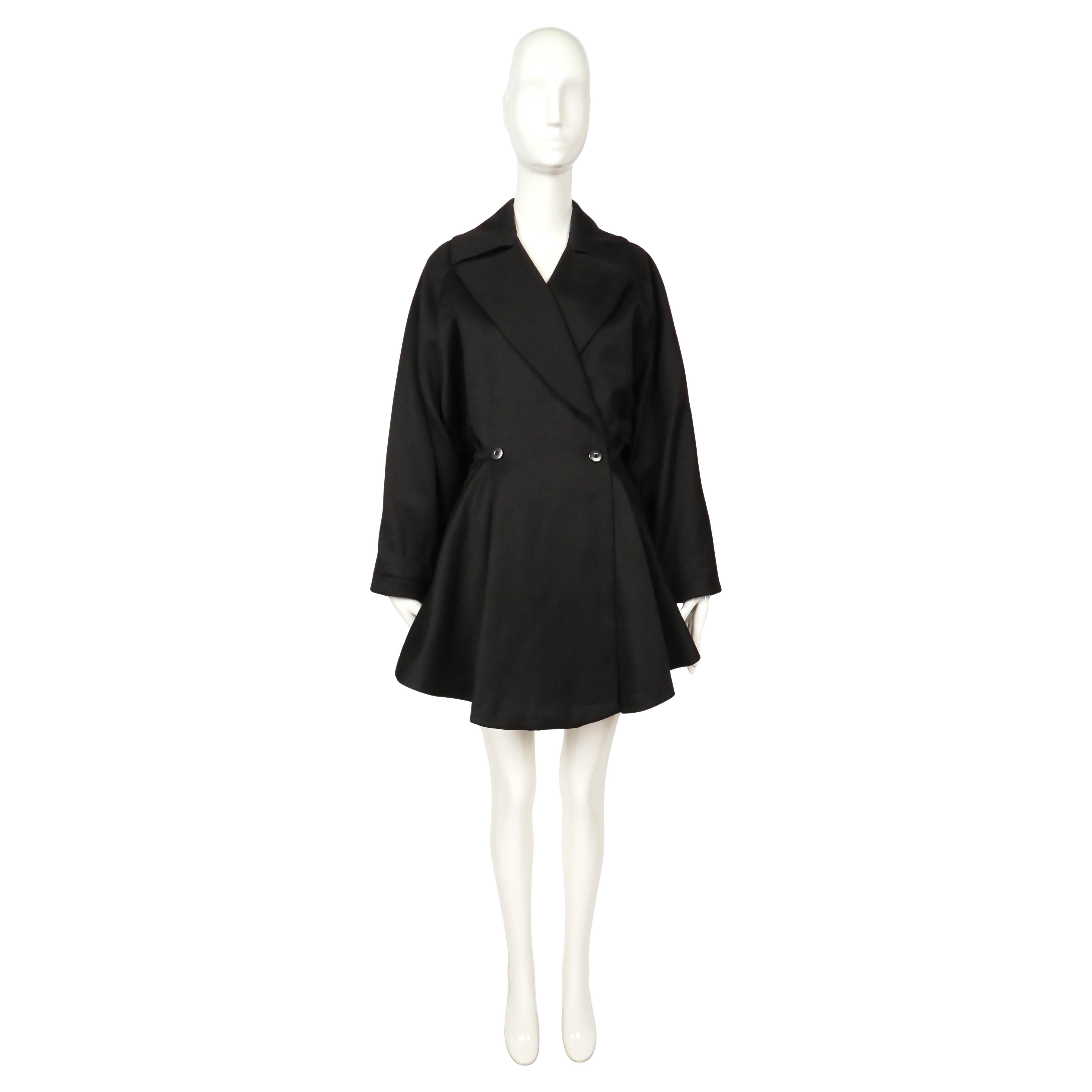 Rarissimo cappotto in lana nera disegnato da Azzedine Alaïa per la collezione di sfilate del 1985. Questo pezzo scultoreo dimostra la celebre padronanza delle proporzioni e della struttura di Alaïa, con un drammatico orlo svasato che crea una